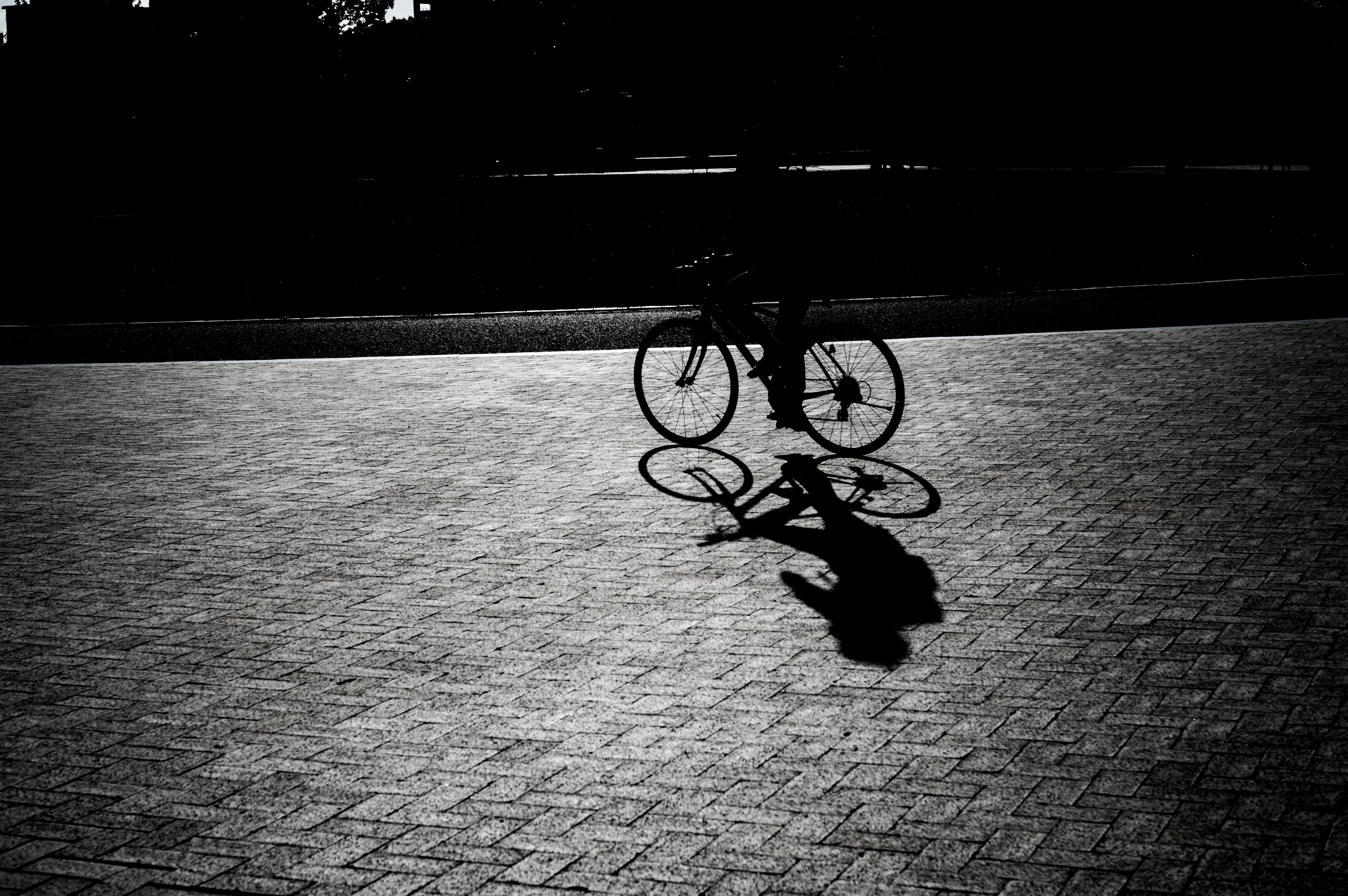 Silhouette eines Fahrrads, das einen Schatten auf einem gepflasterten Weg wirft