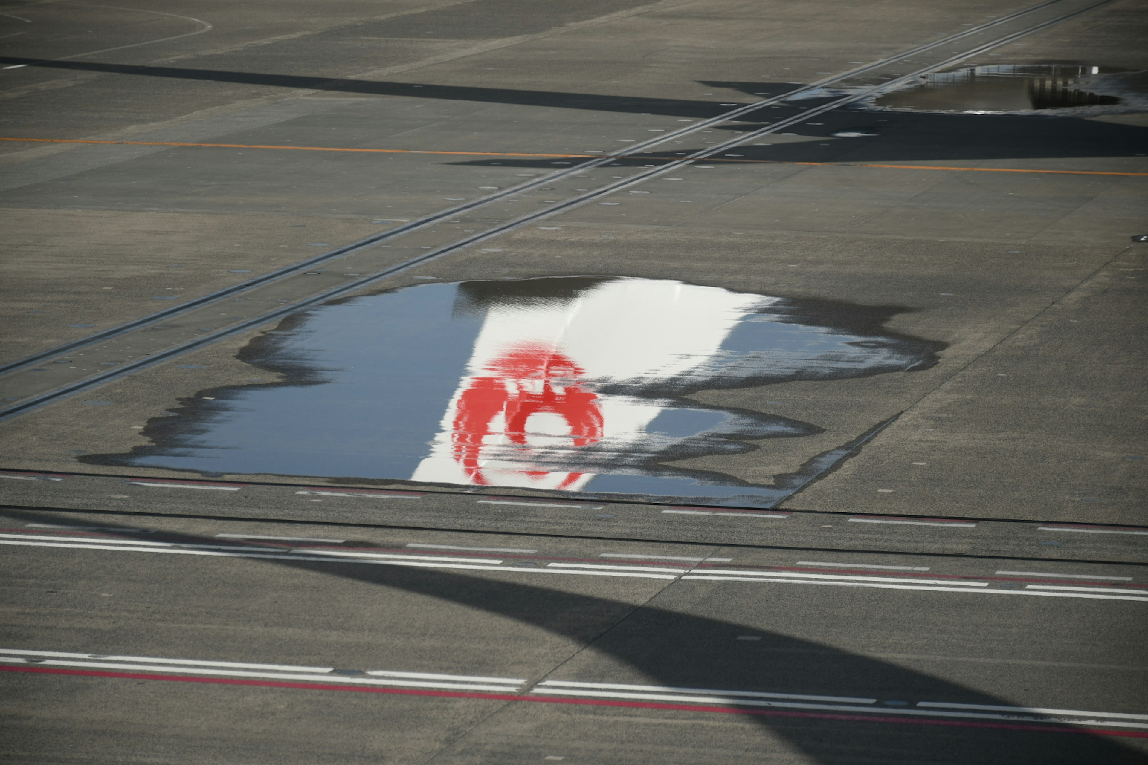 空港の滑走路に映る日本の国旗の水たまり