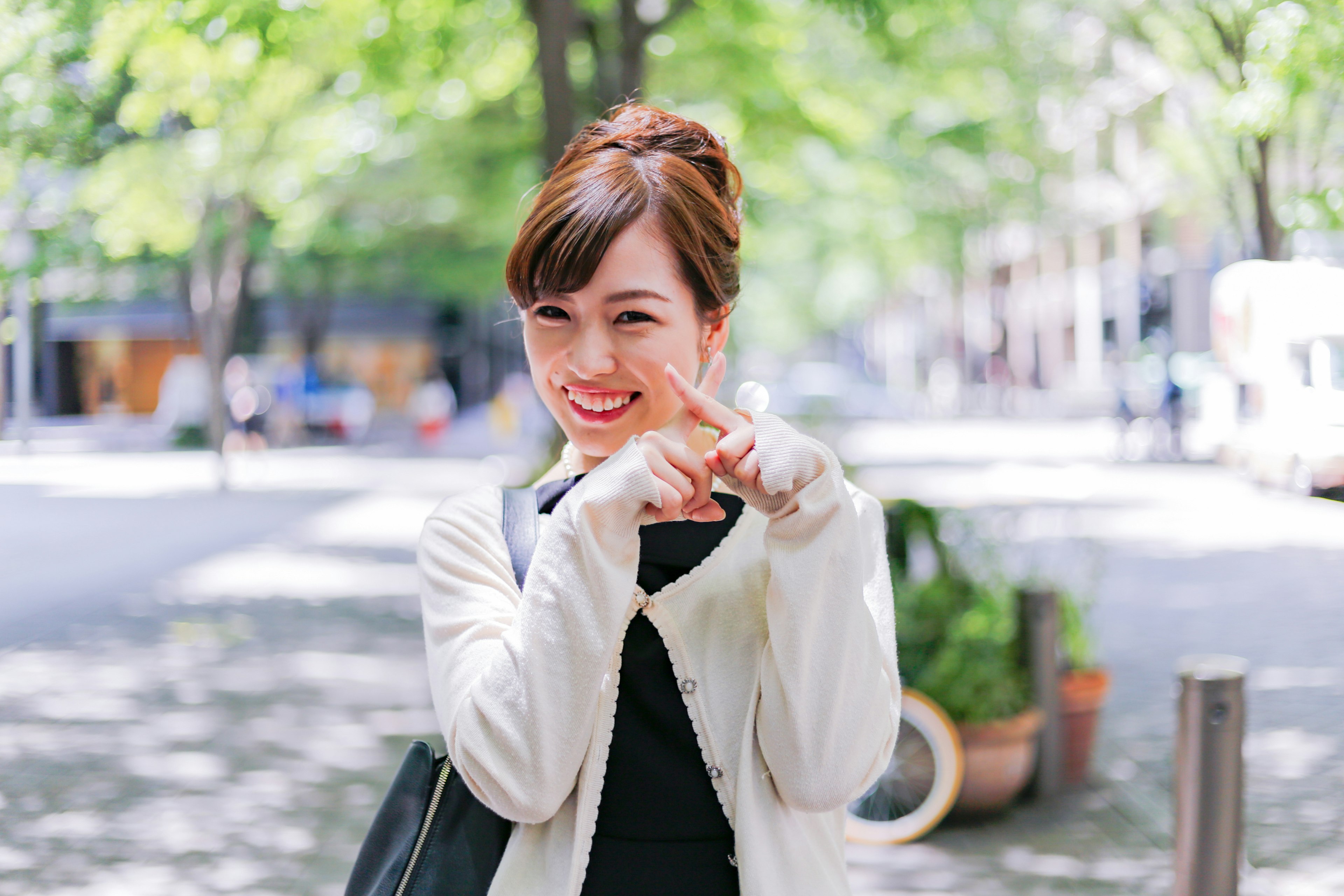 A smiling woman pointing her fingers in a park