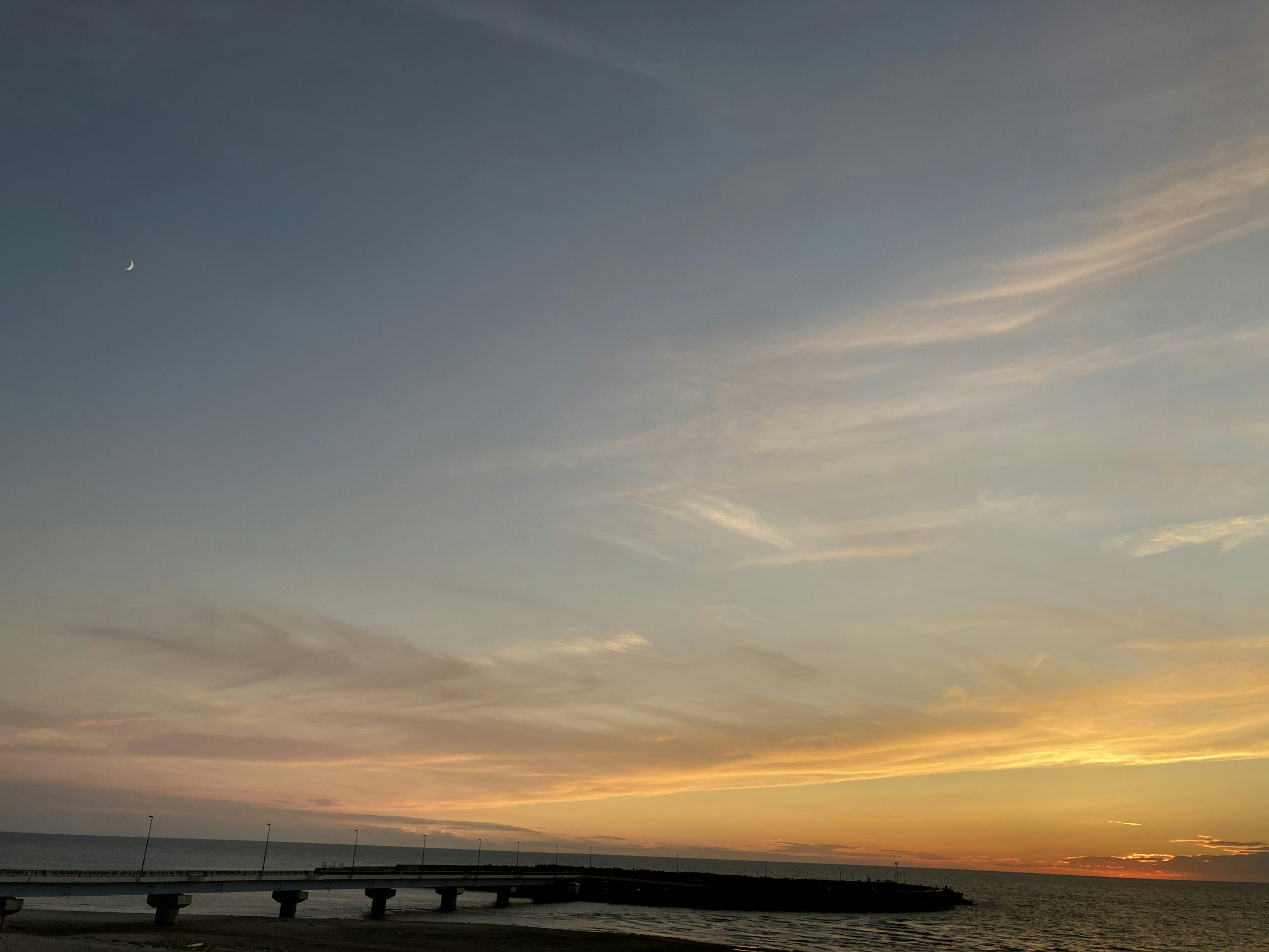 Hermoso cielo al atardecer sobre el océano con un puente que se extiende en el agua