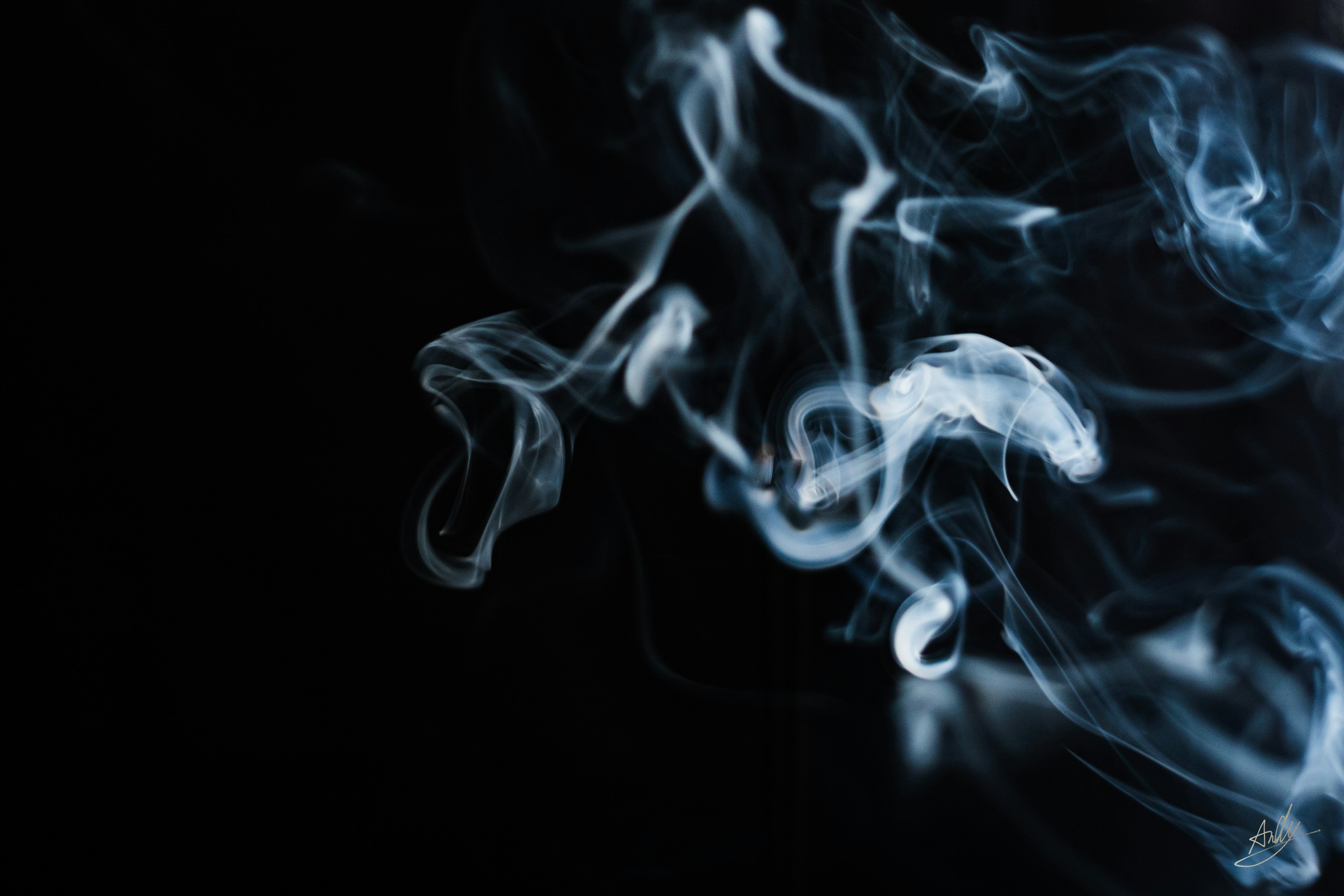 Flow of blue-white smoke against a black background