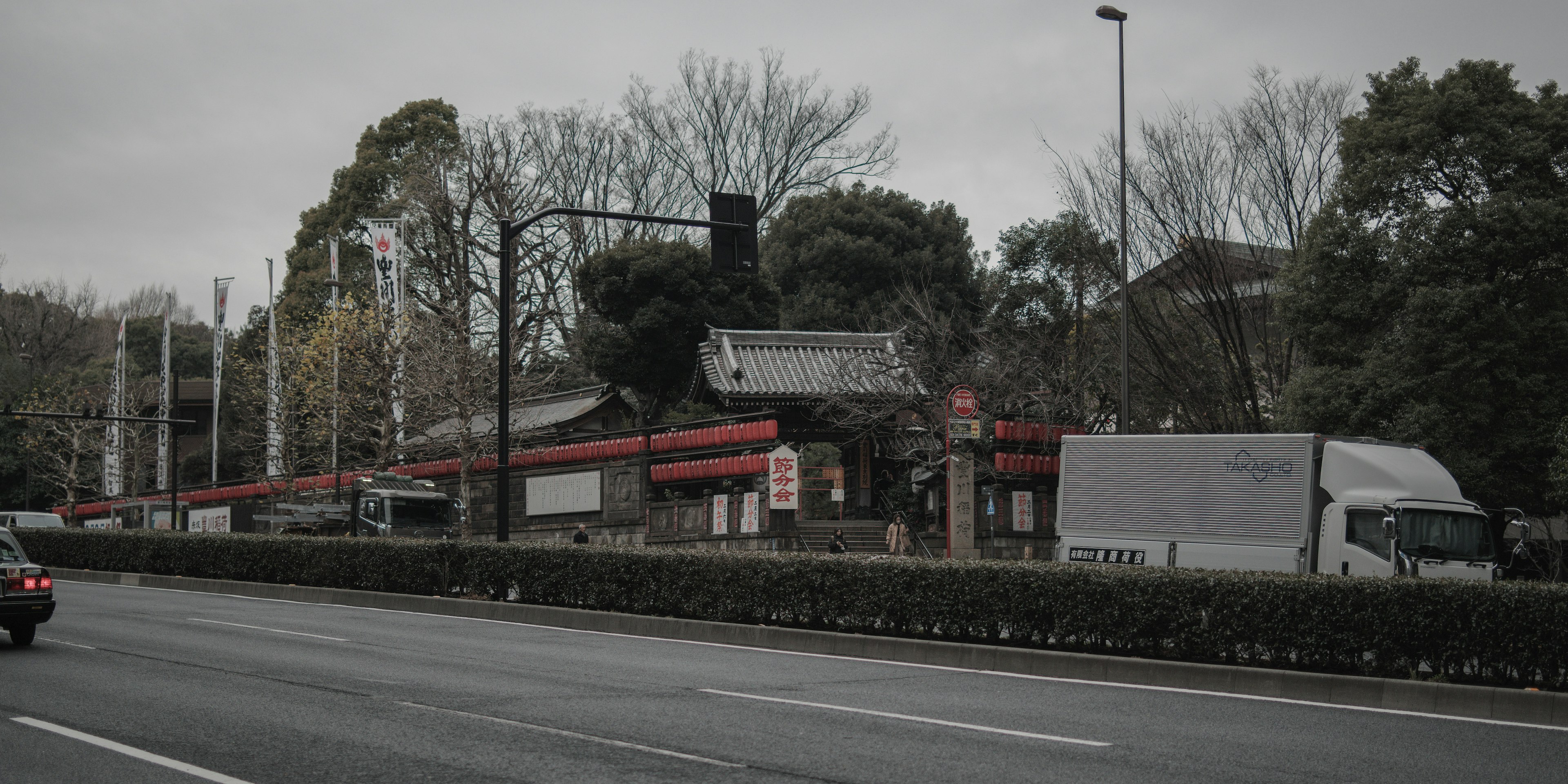 Street scene featuring a building with a red roof and a passing truck