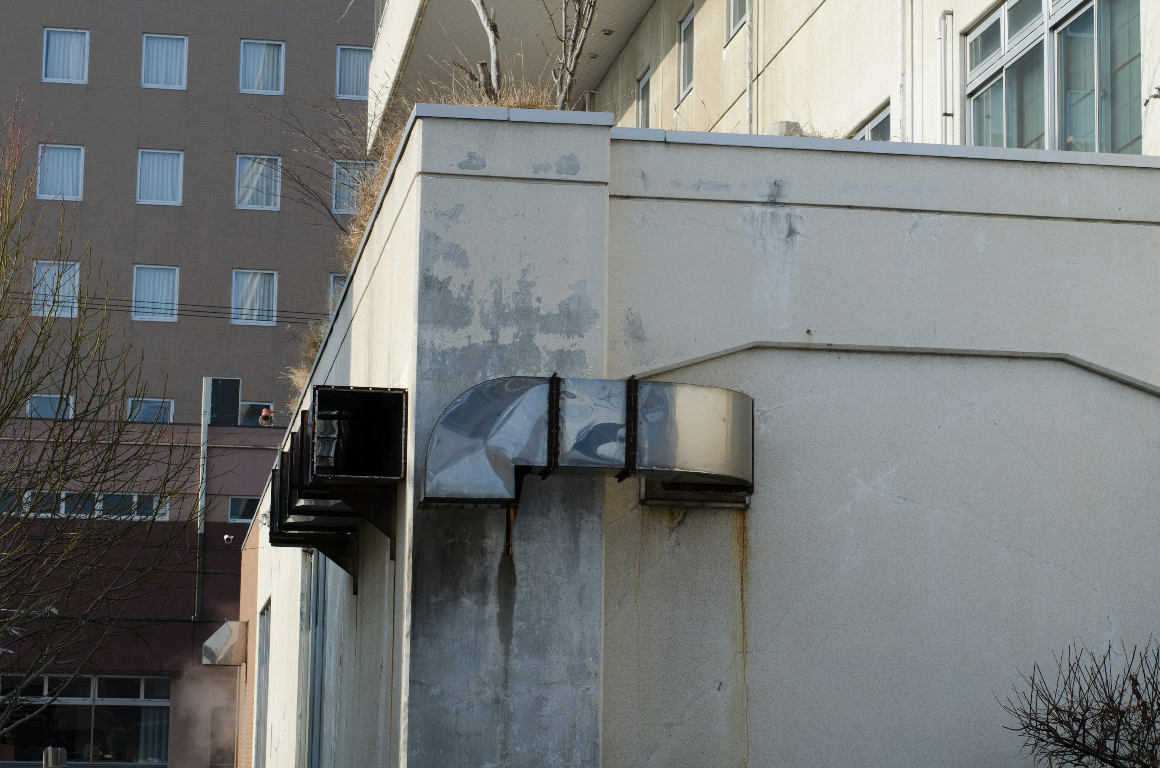 Metallstruktur an einer weißen Wand mit umliegenden Gebäuden