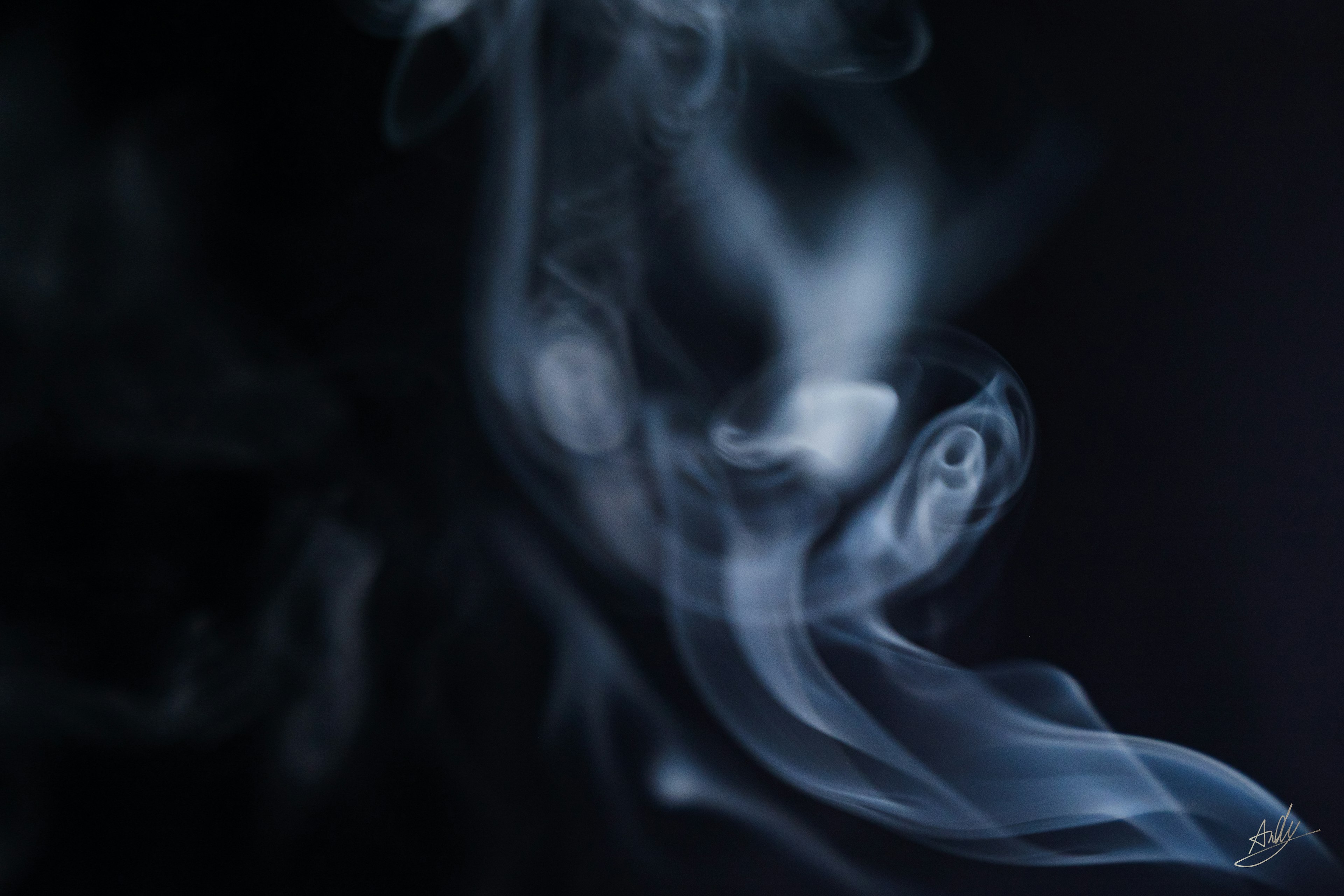 Wispy blue-gray smoke curling against a black background