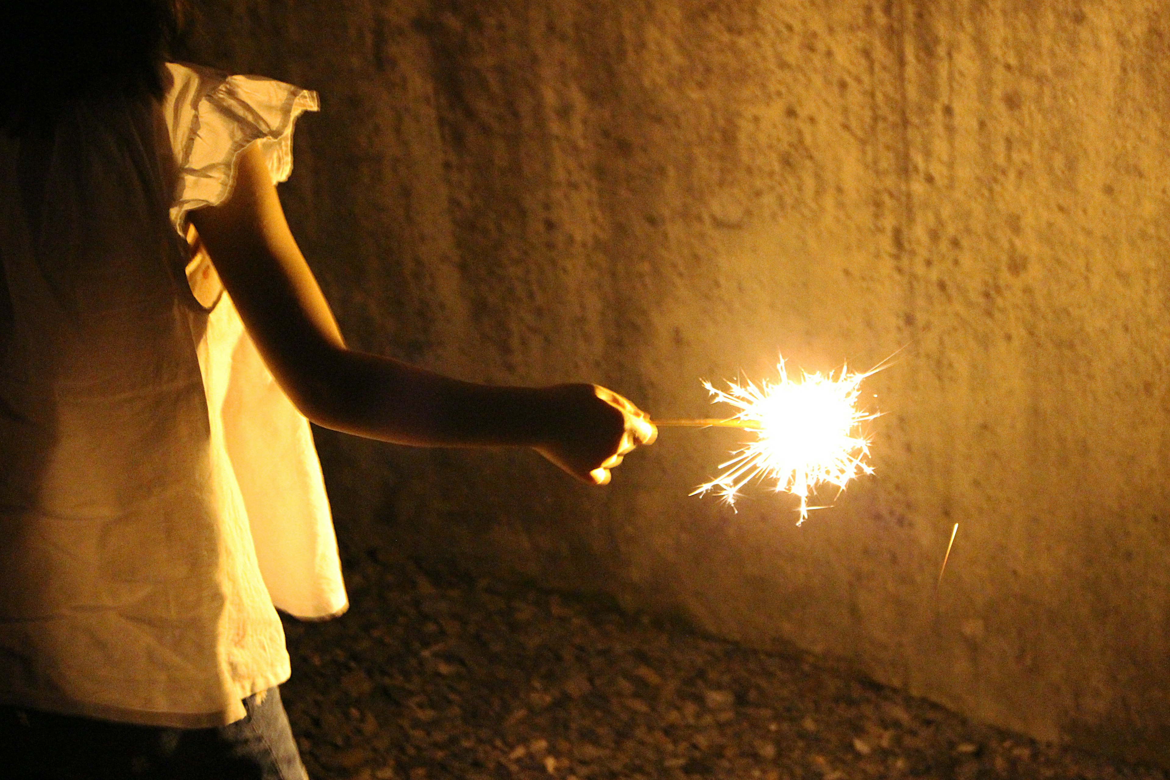 Silhouette of a child holding a sparkler against a dark background