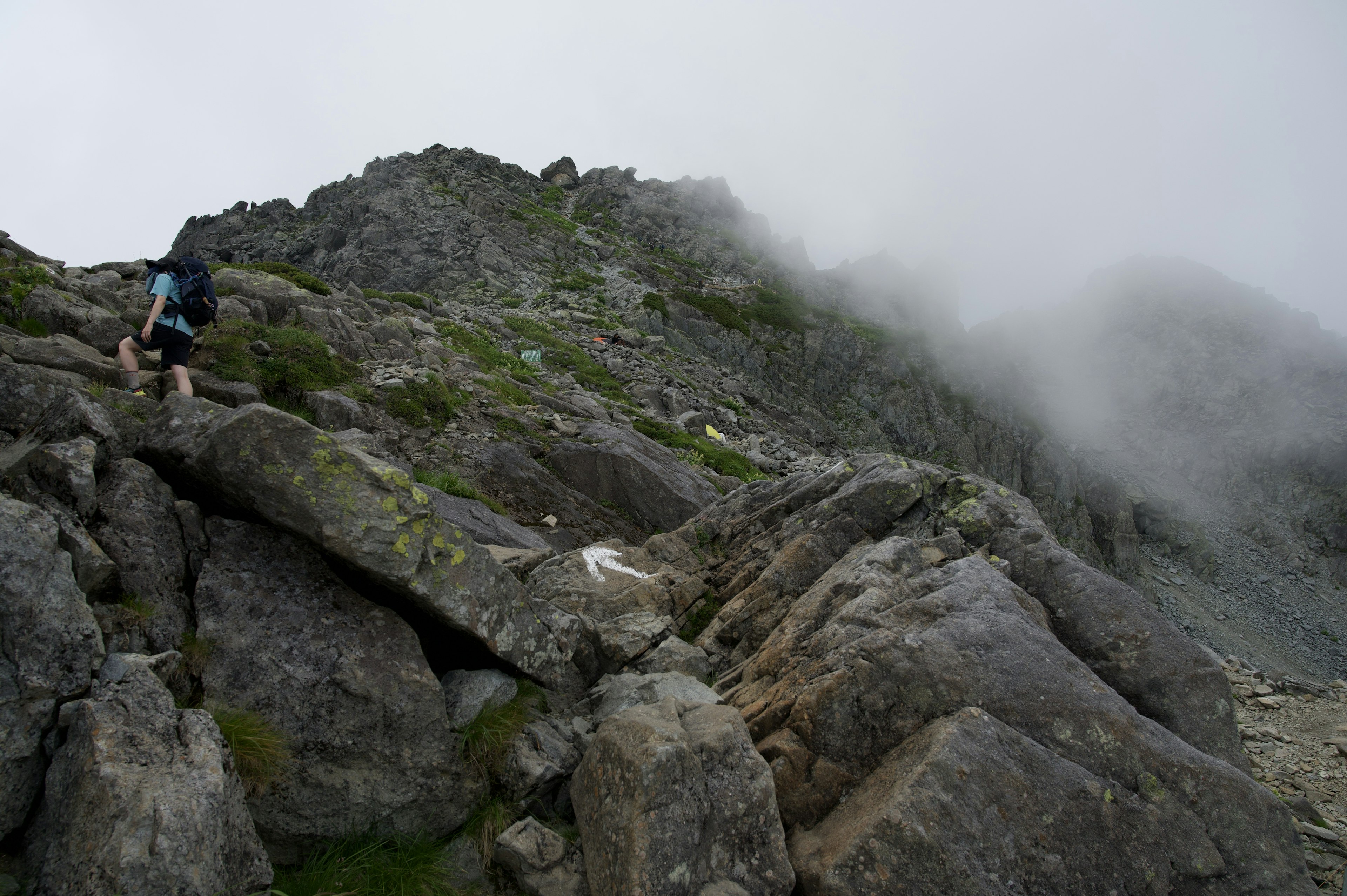 Hiker climbing a rocky mountain slope shrouded in mist