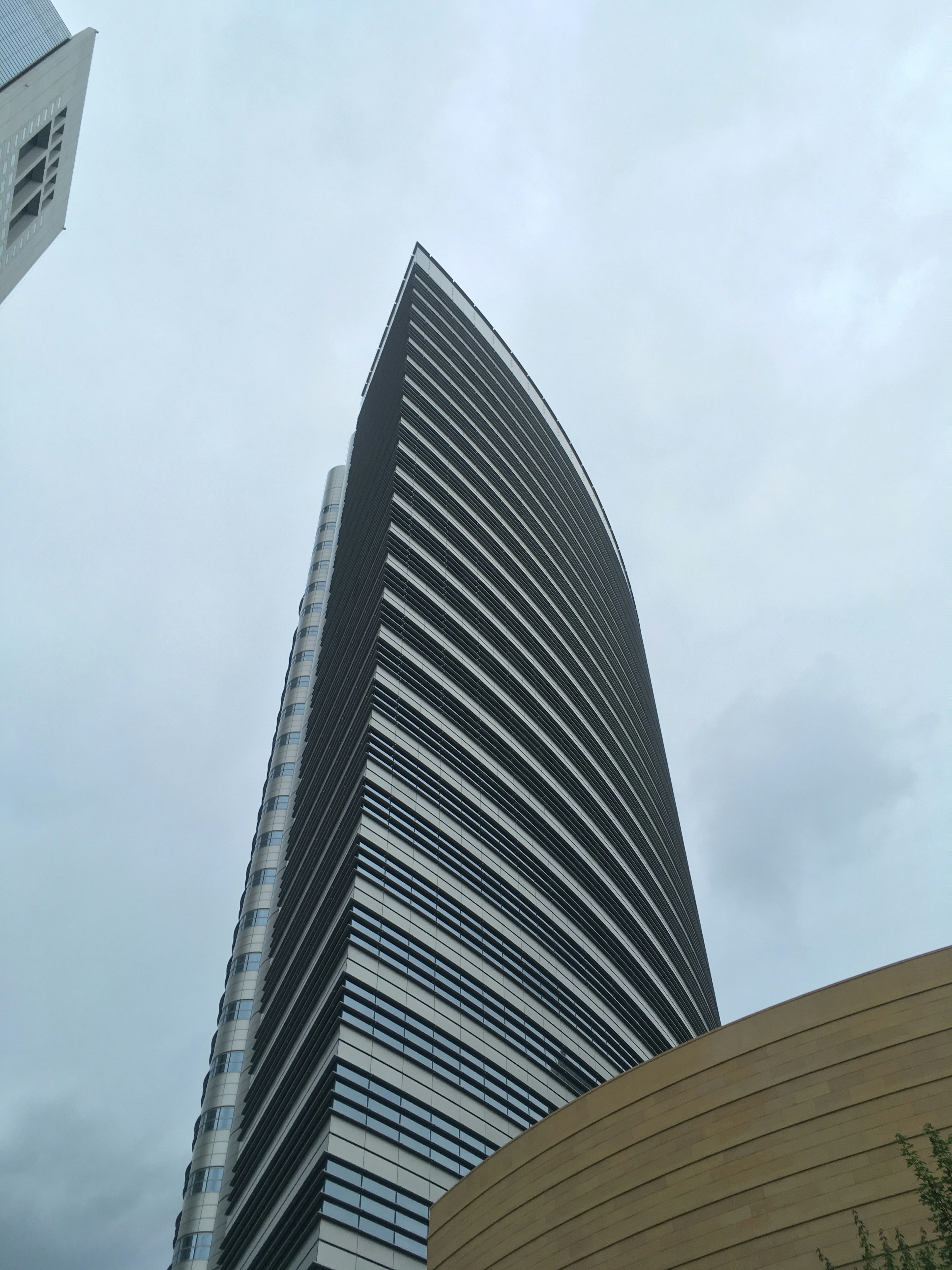 Edificio alto con fachada curva bajo un cielo nublado