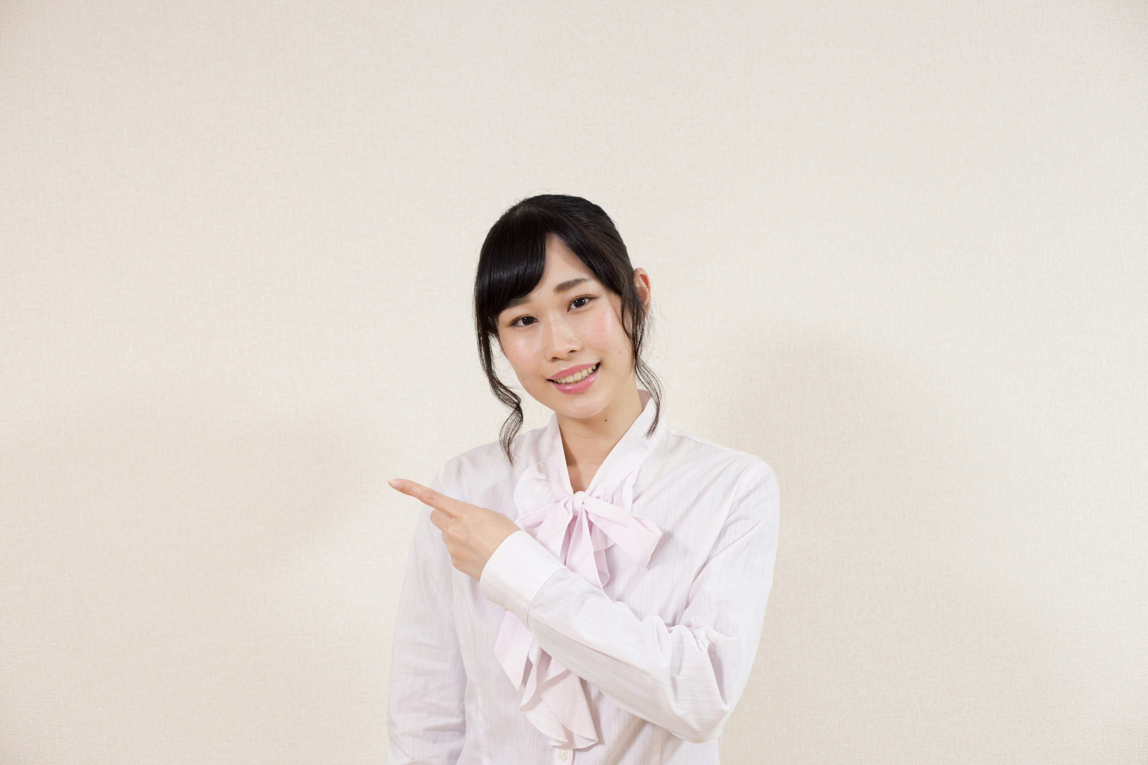 A woman in a white shirt smiling and pointing