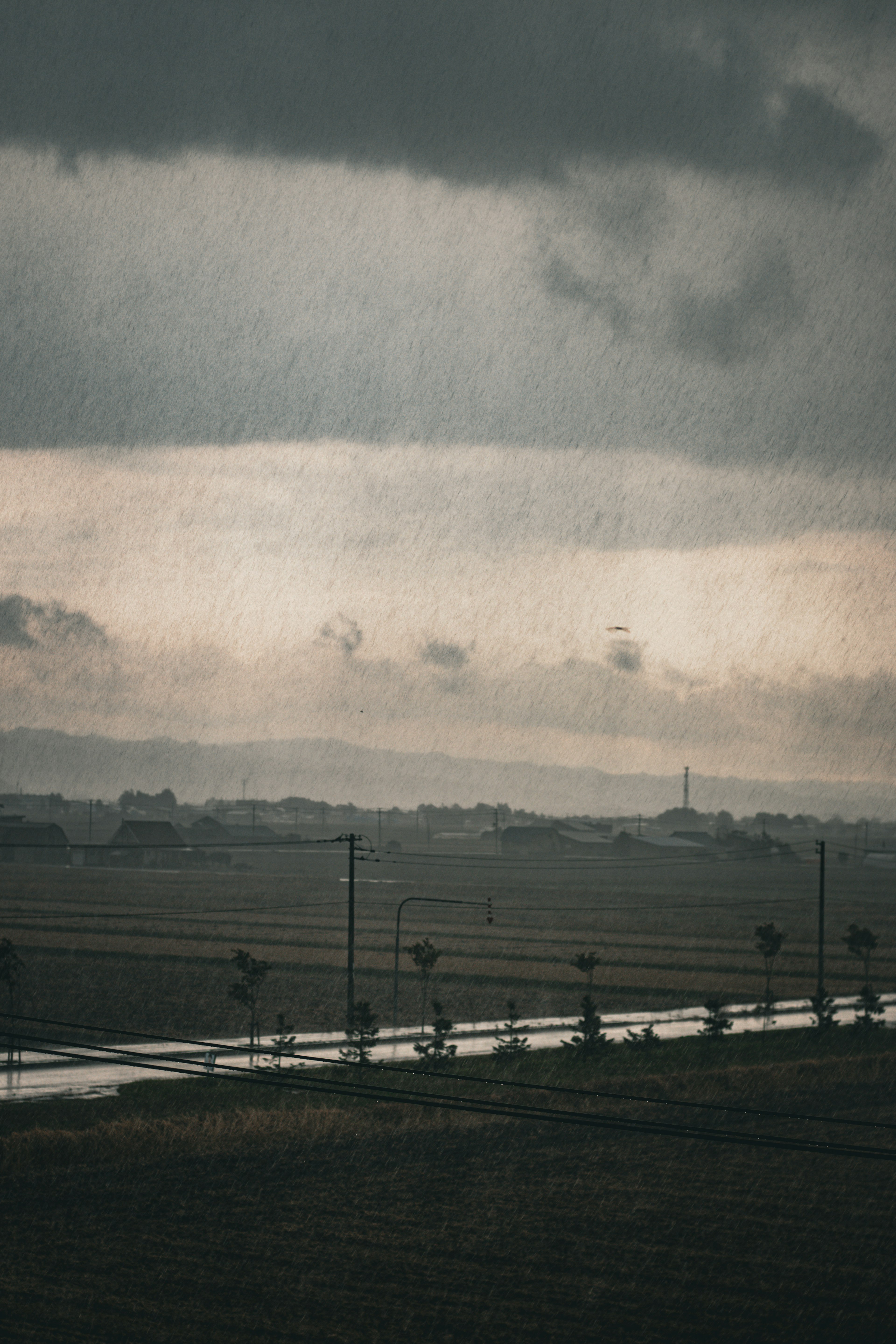 暗い雲に覆われた風景と遠くの村のシルエット