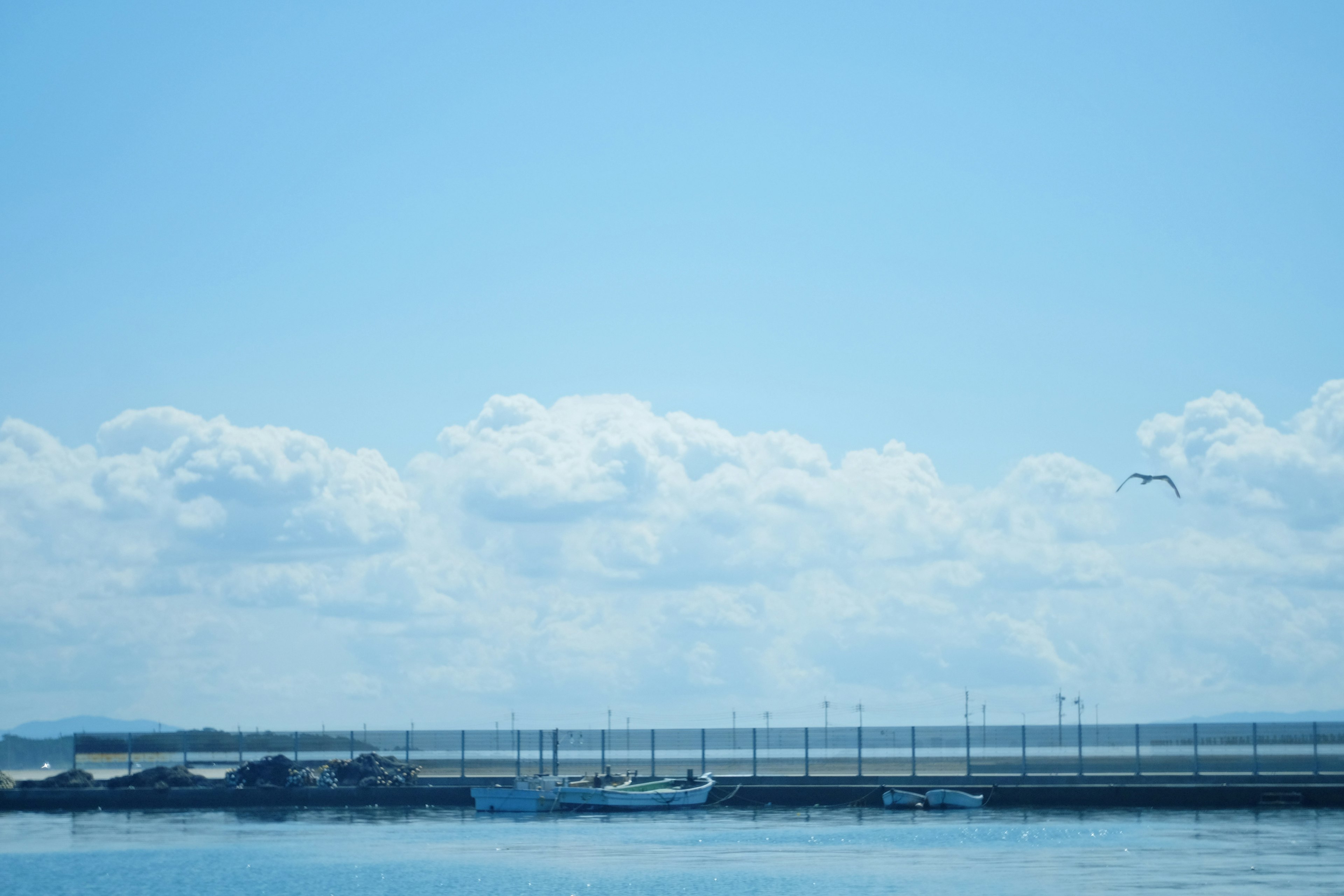 青空と雲の下に浮かぶ小さなボートがある静かな海の風景