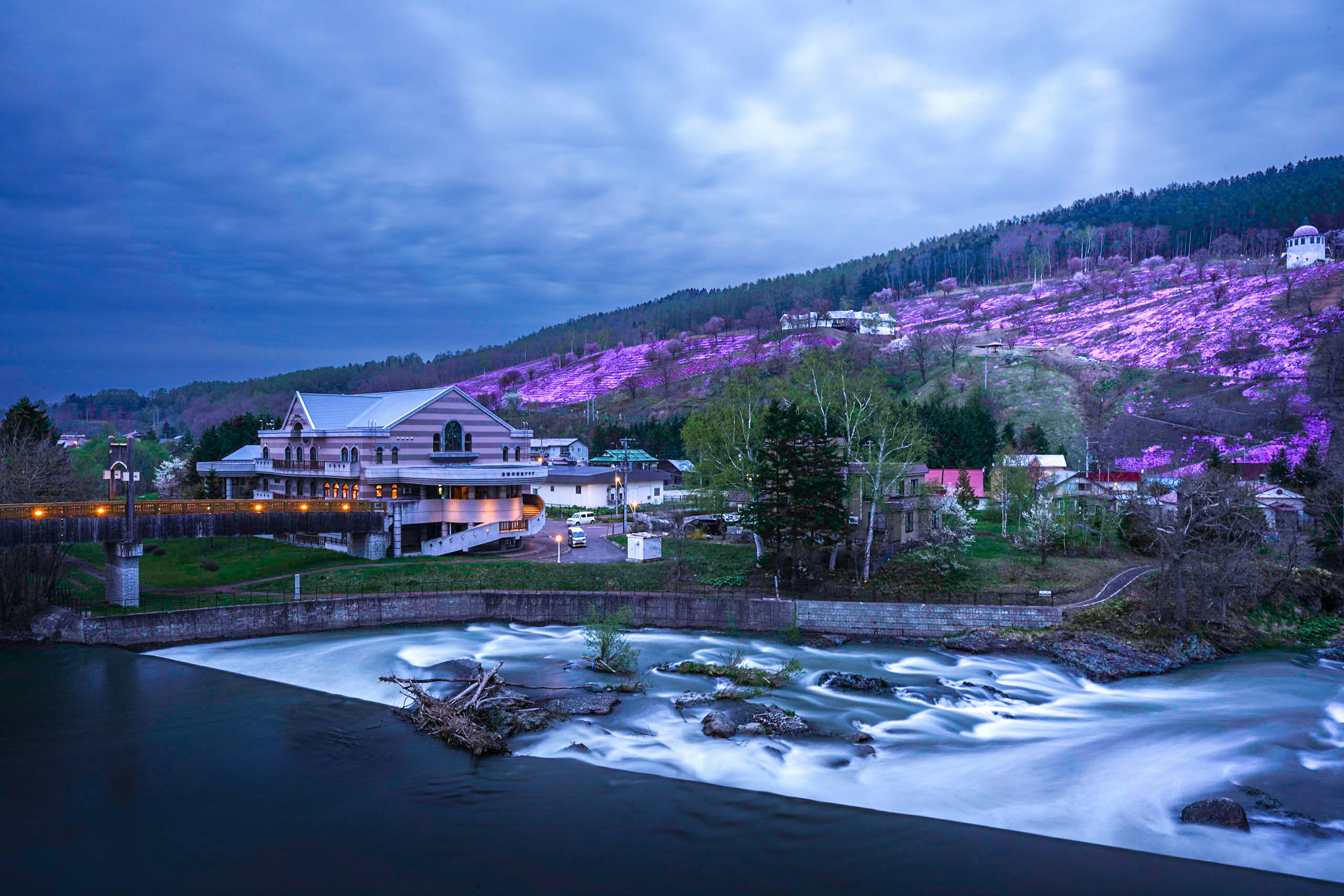 Vista panoramica di un fiume che scorre con una collina viola al crepuscolo