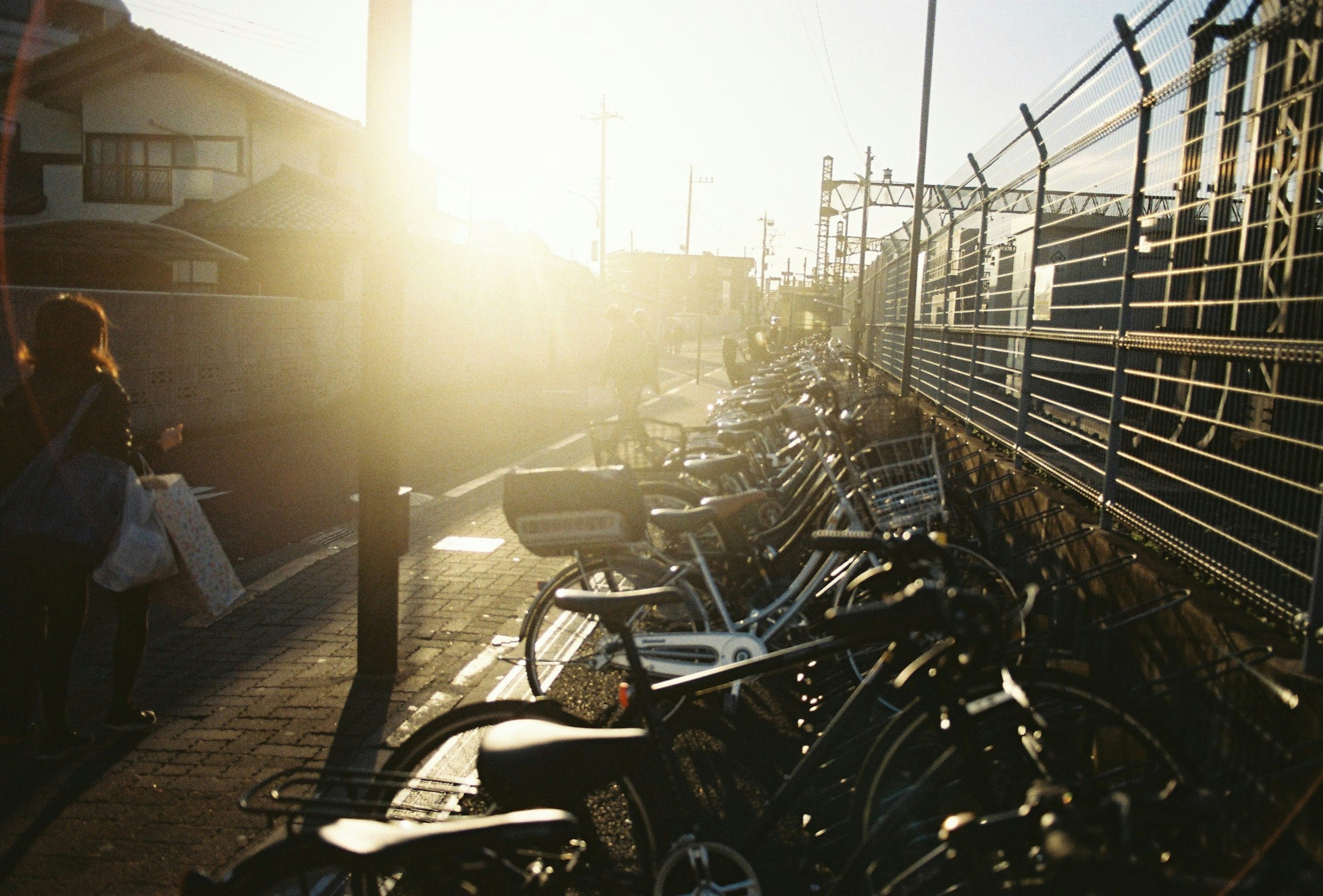 夕日が照らす自転車置き場と人々の姿