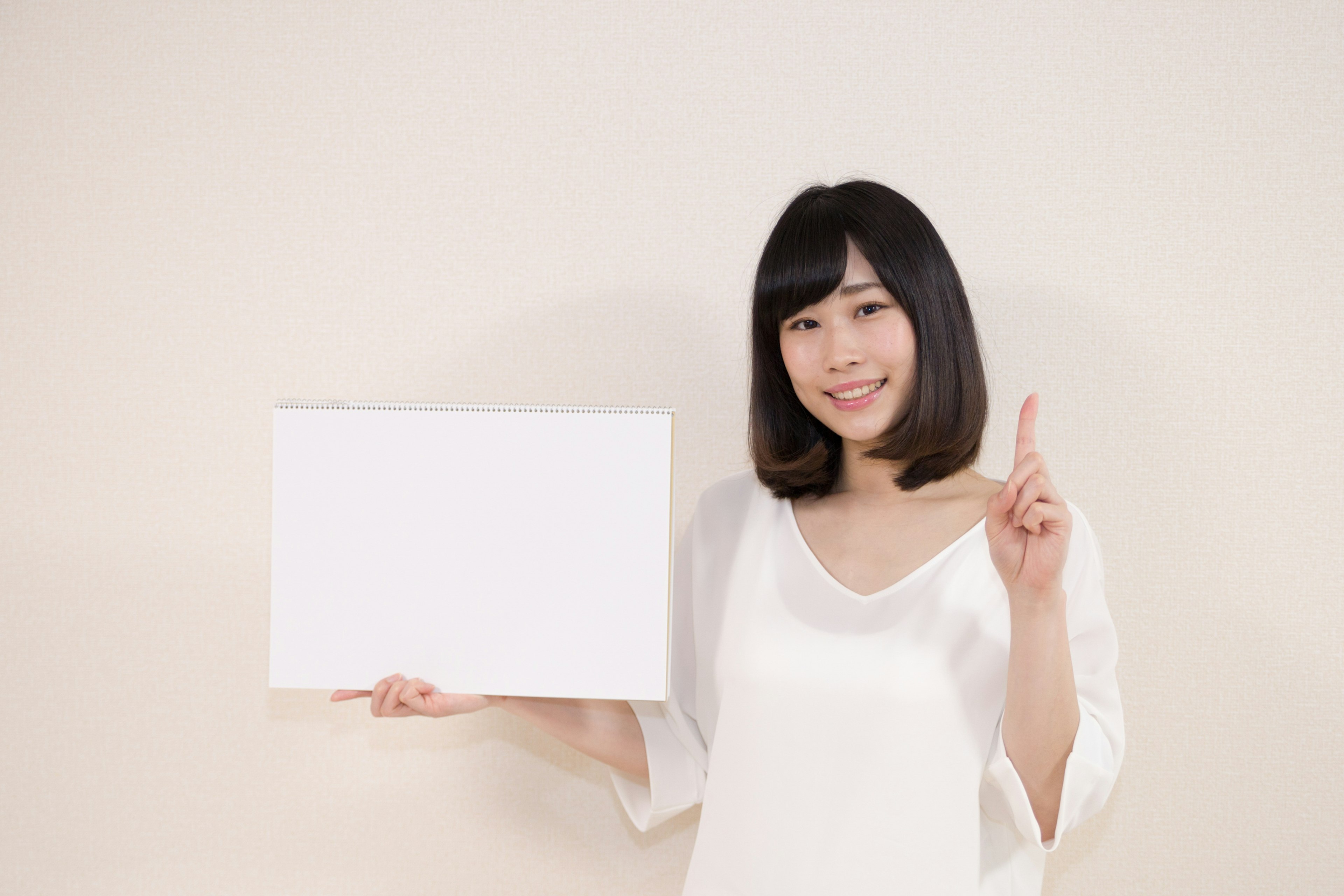 Une femme tenant un tableau vide devant un fond blanc