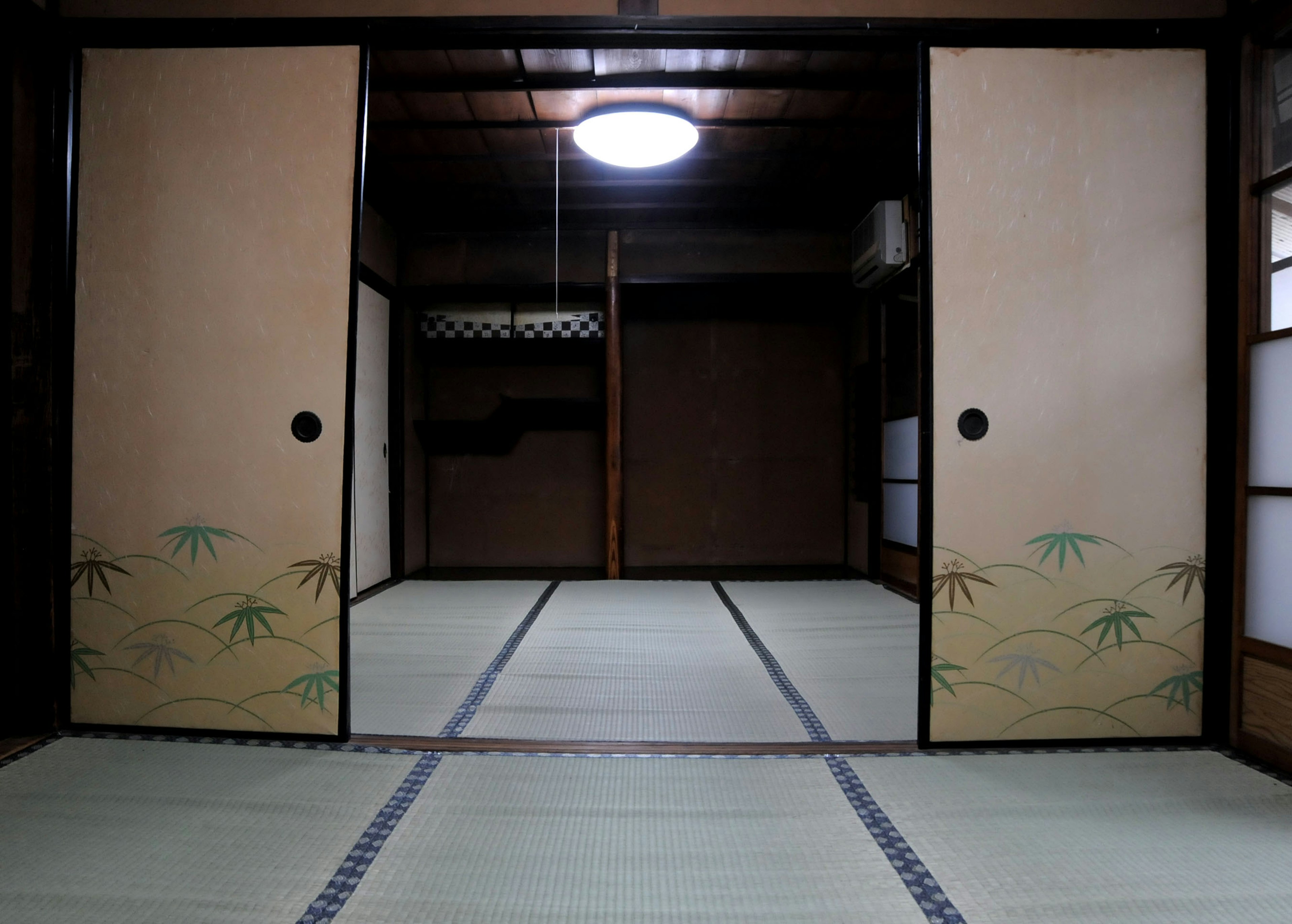 Interior ruang tradisional Jepang dengan pintu geser dan lantai tatami yang dihiasi bambu