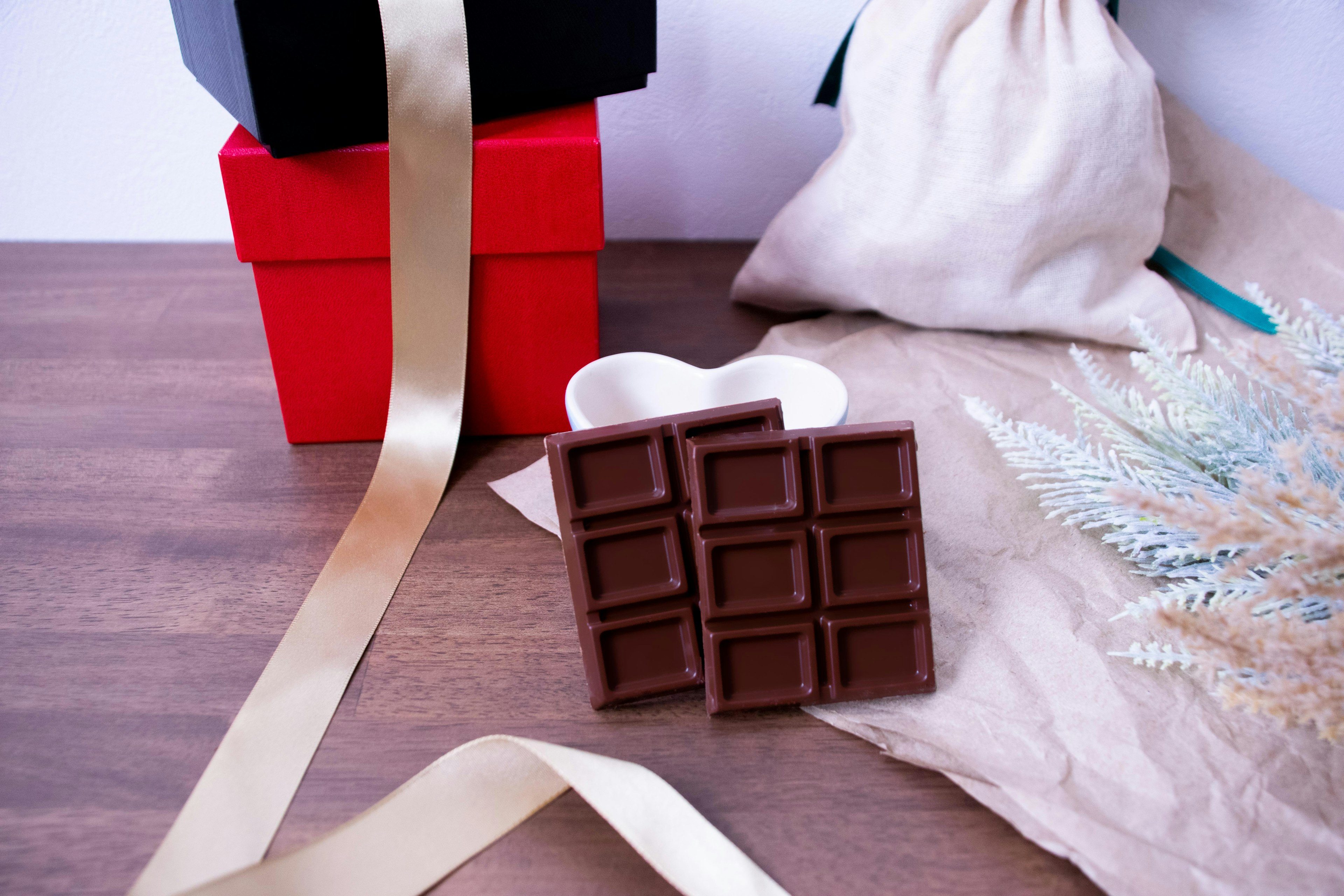 Arrangement of chocolate bar with red and black gift boxes and gold ribbon