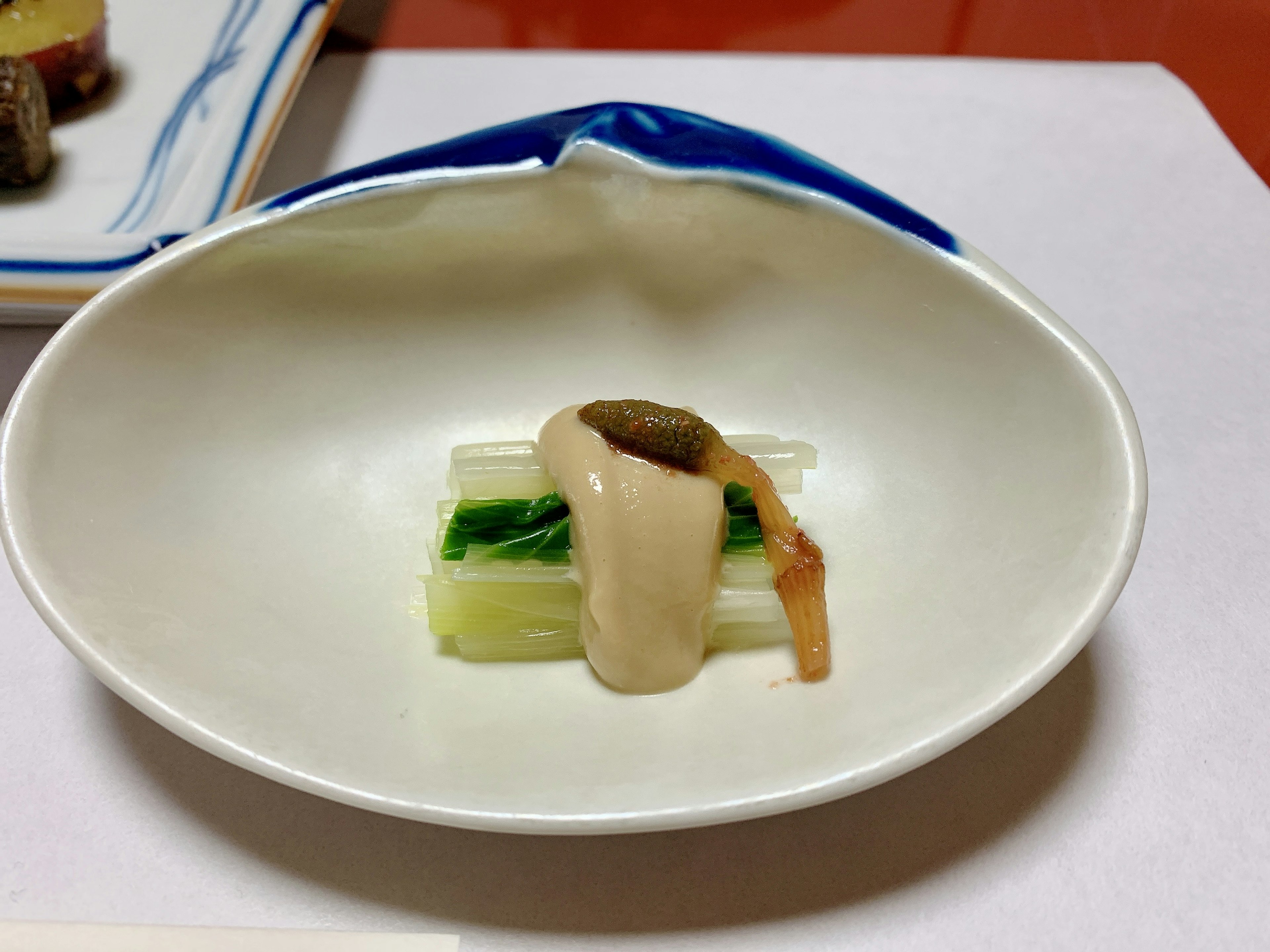 Dish served on a white plate featuring green vegetables and white sauce