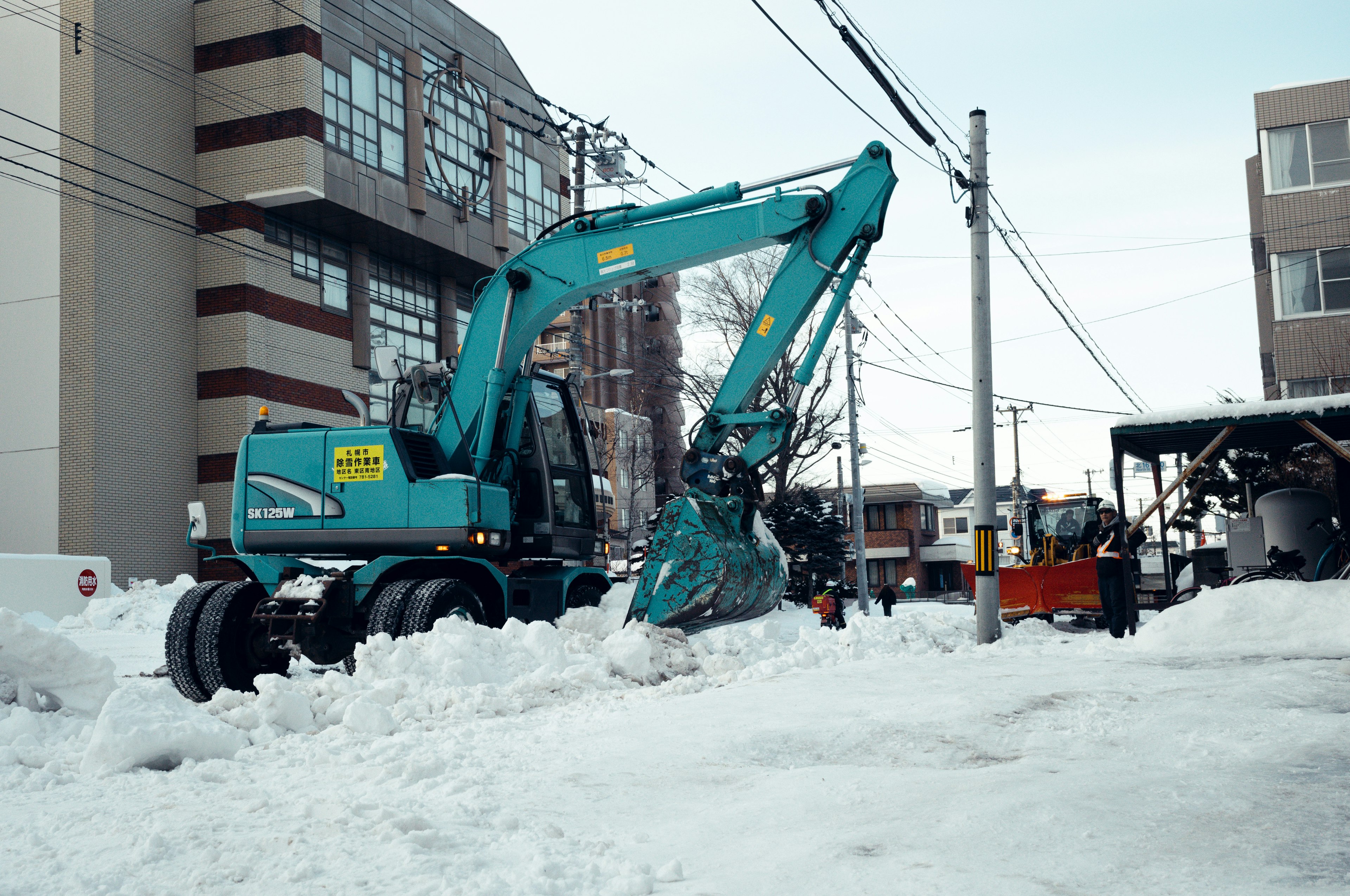 蓝色挖掘机在清理街道上的雪