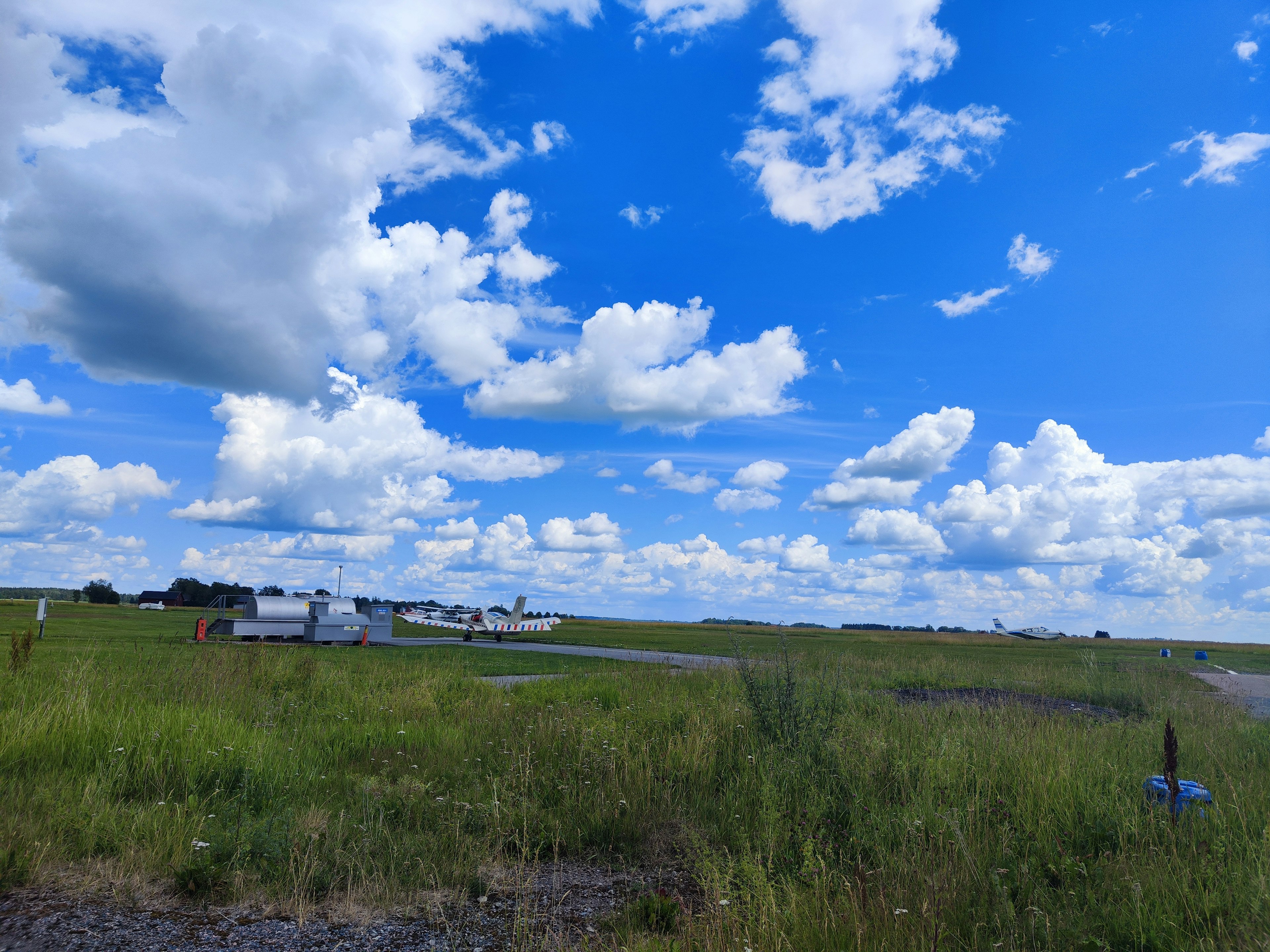 Paysage vaste avec ciel bleu nuages blancs herbe verte et petit avion