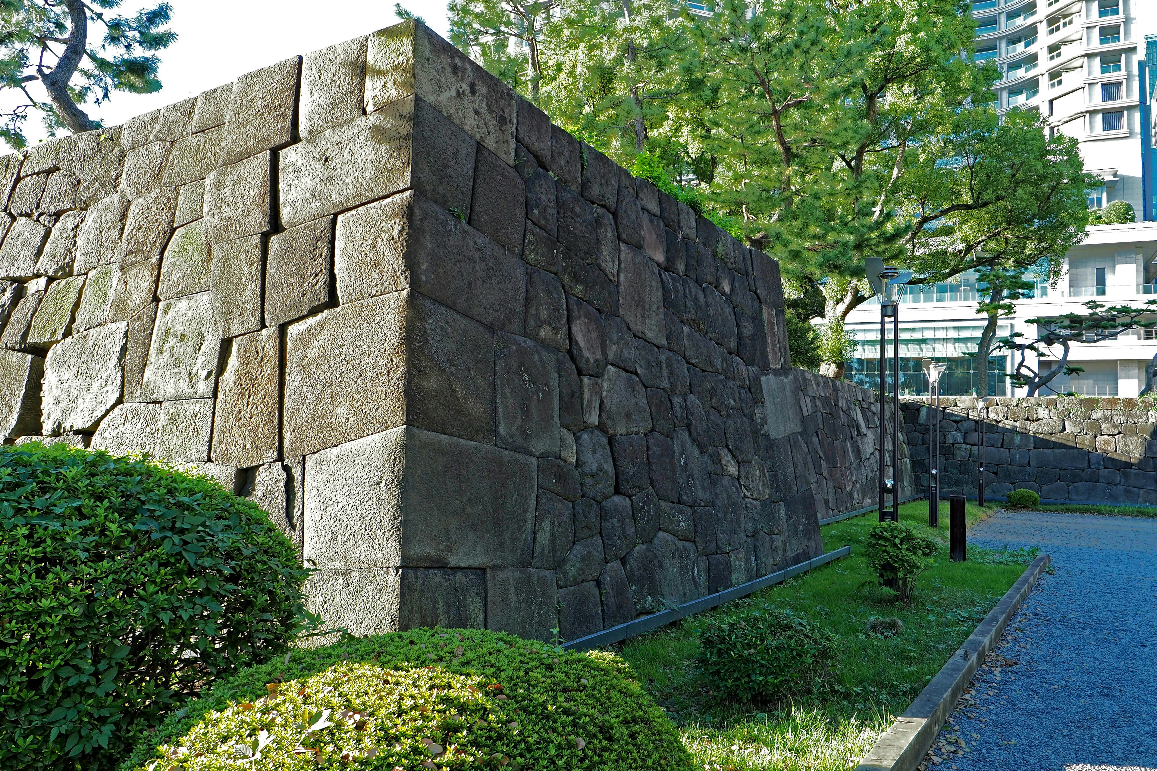 石造りの古い城壁と緑の植栽がある公園の風景