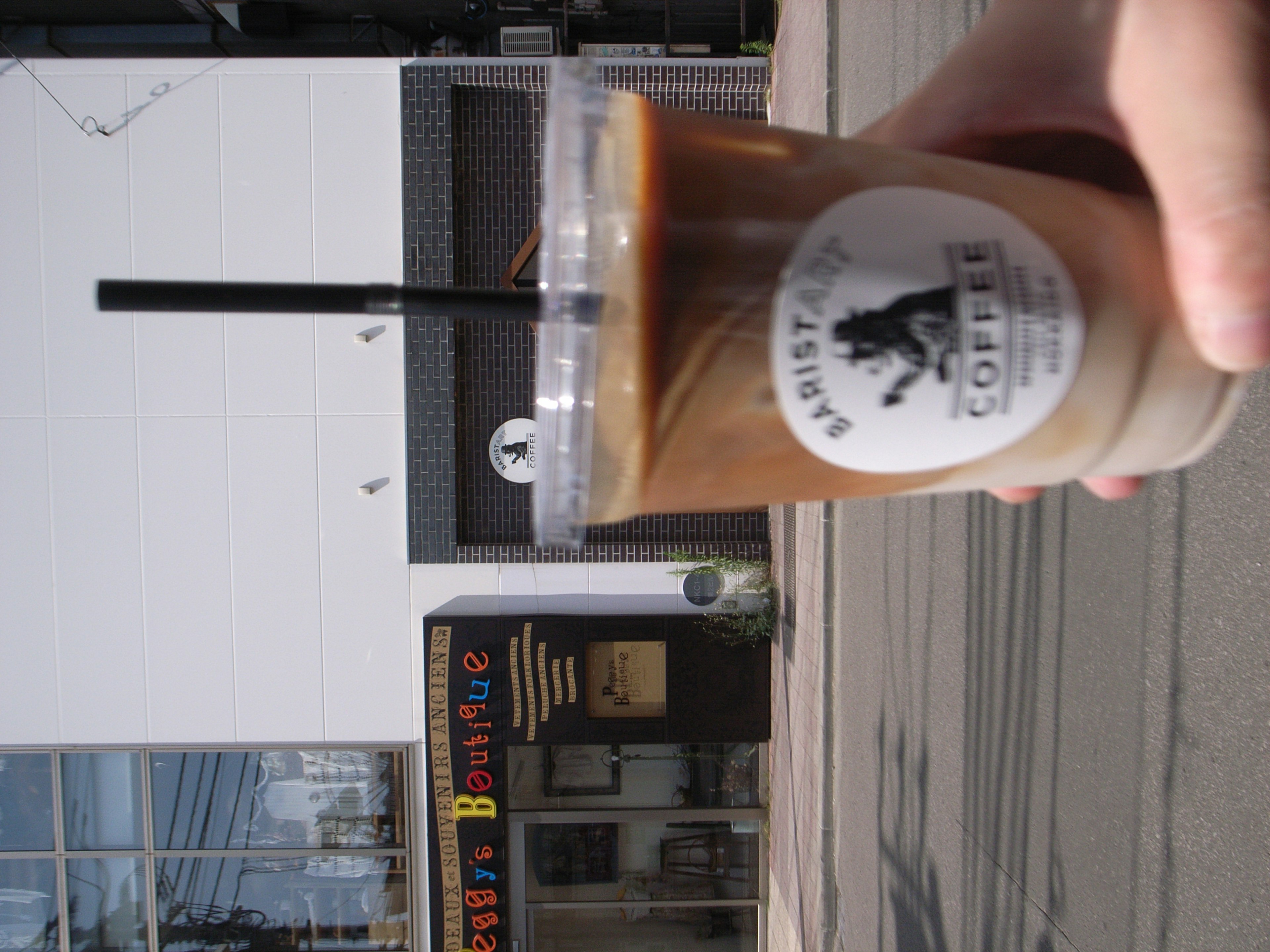 Eine Hand, die einen Eiskaffee hält, mit einem Café-Hintergrund