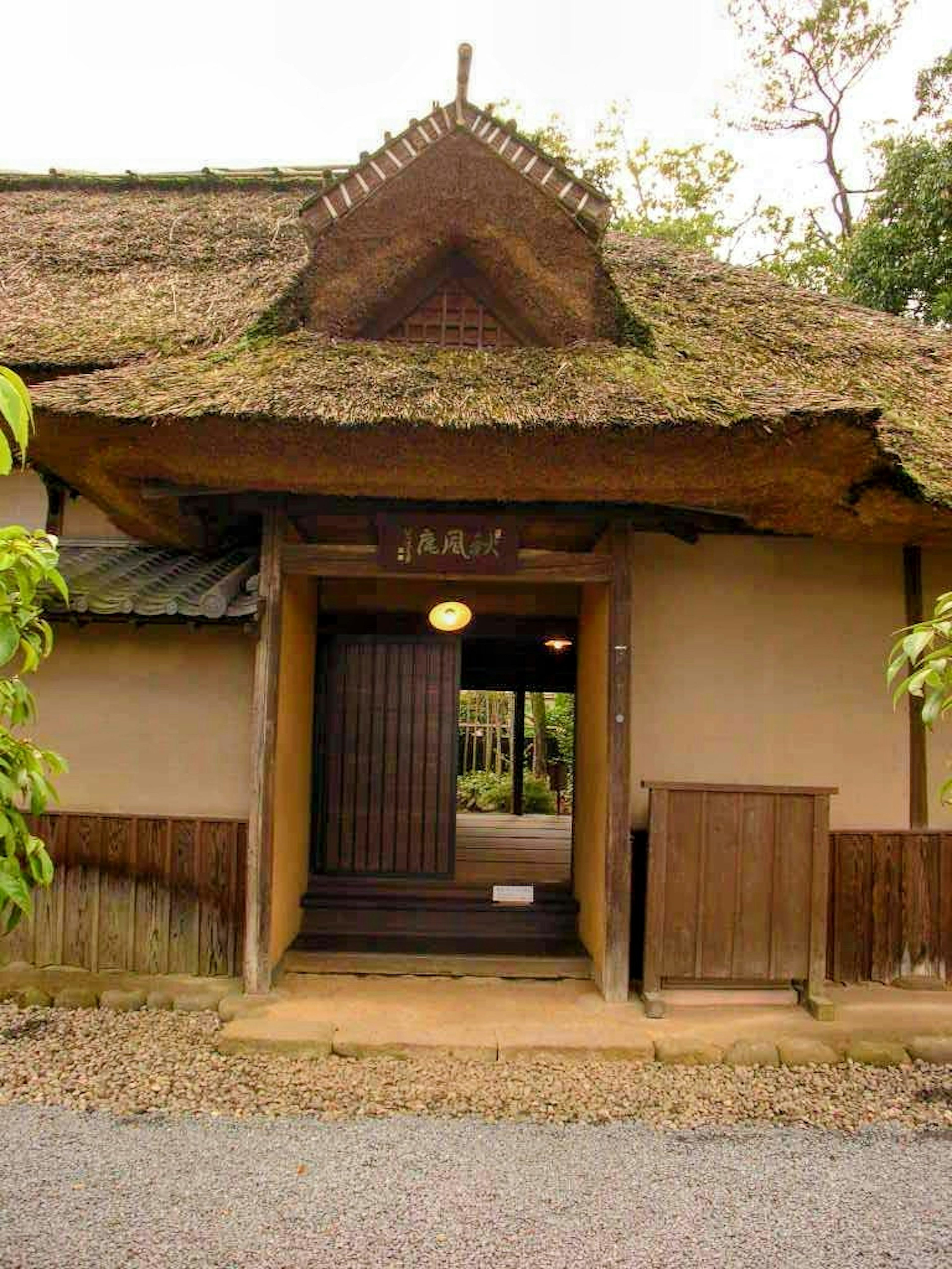 Traditional Japanese house entrance featuring a thatched roof and wooden door