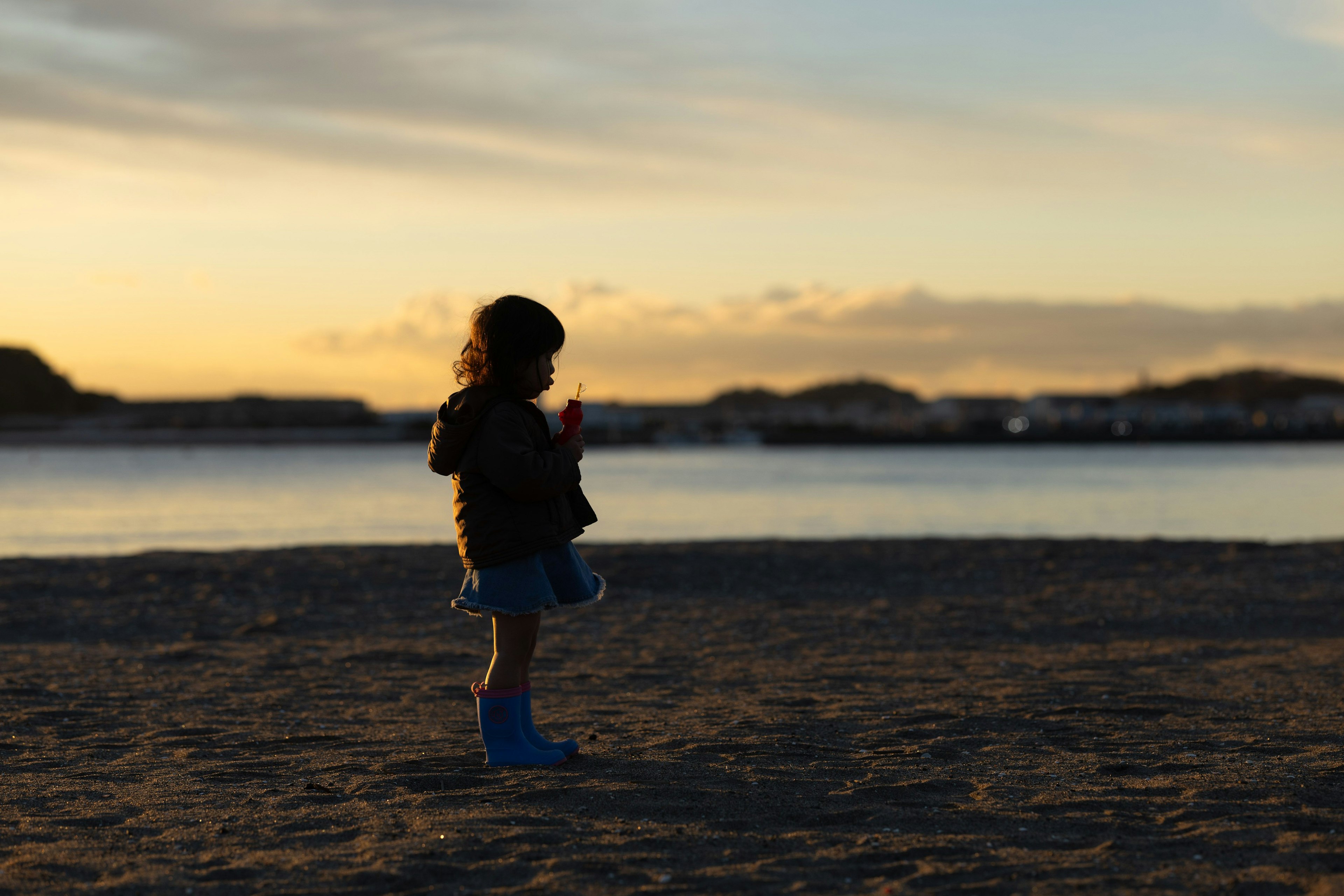 夕暮れの海辺で立っている子供のシルエット