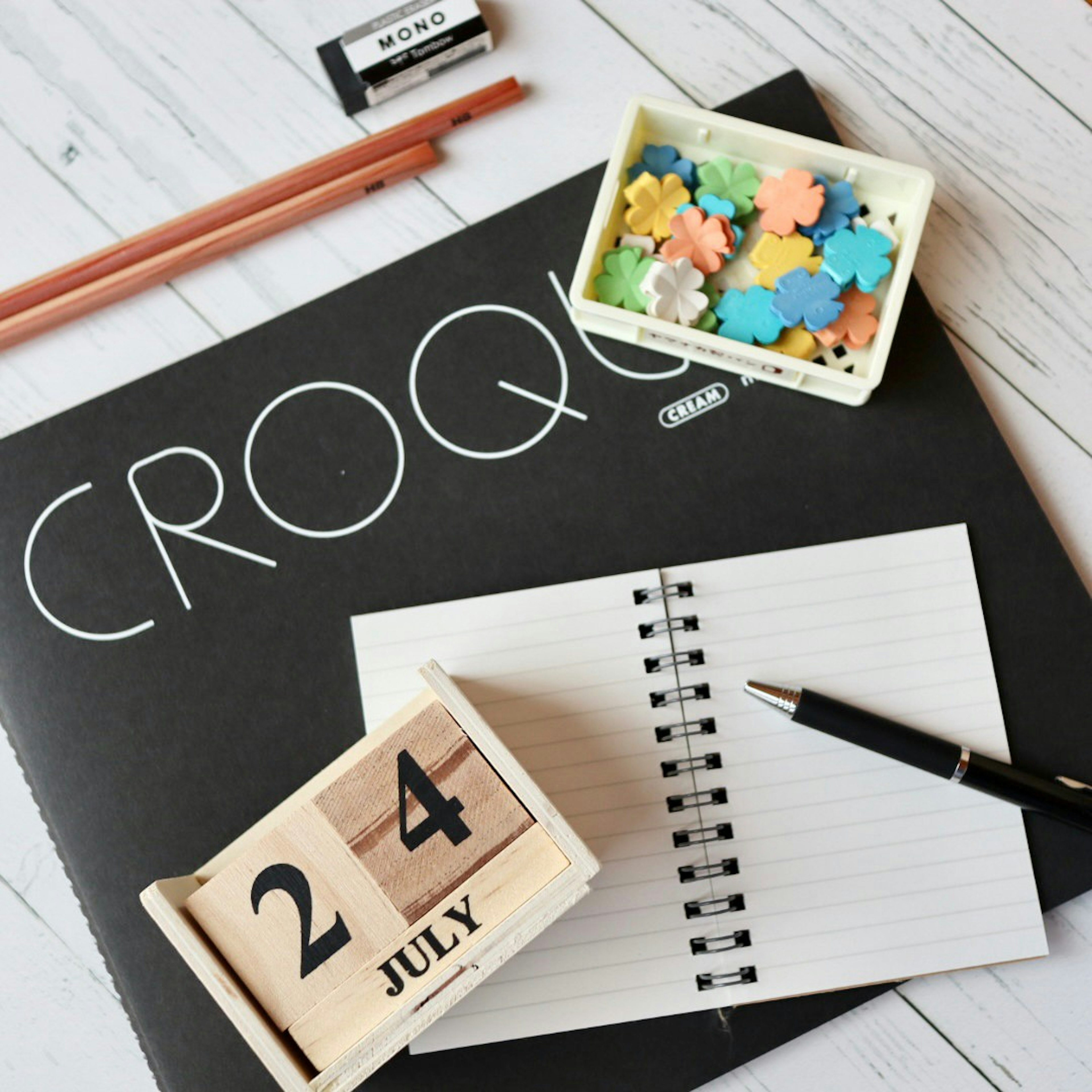 Desk setup featuring a notebook colorful pieces and a wooden calendar