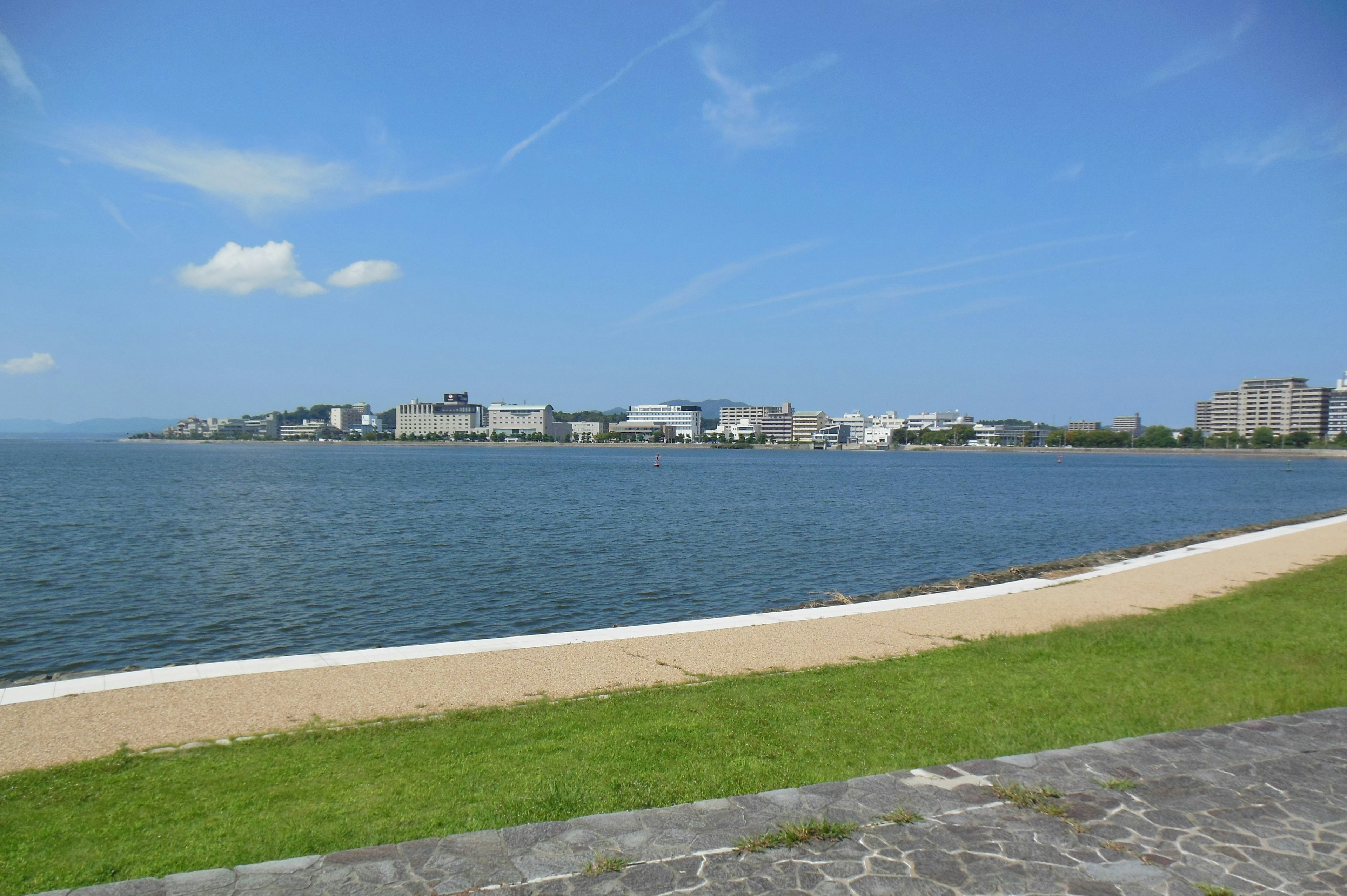 Vista escénica de un mar y cielo azules a lo largo de una orilla verde