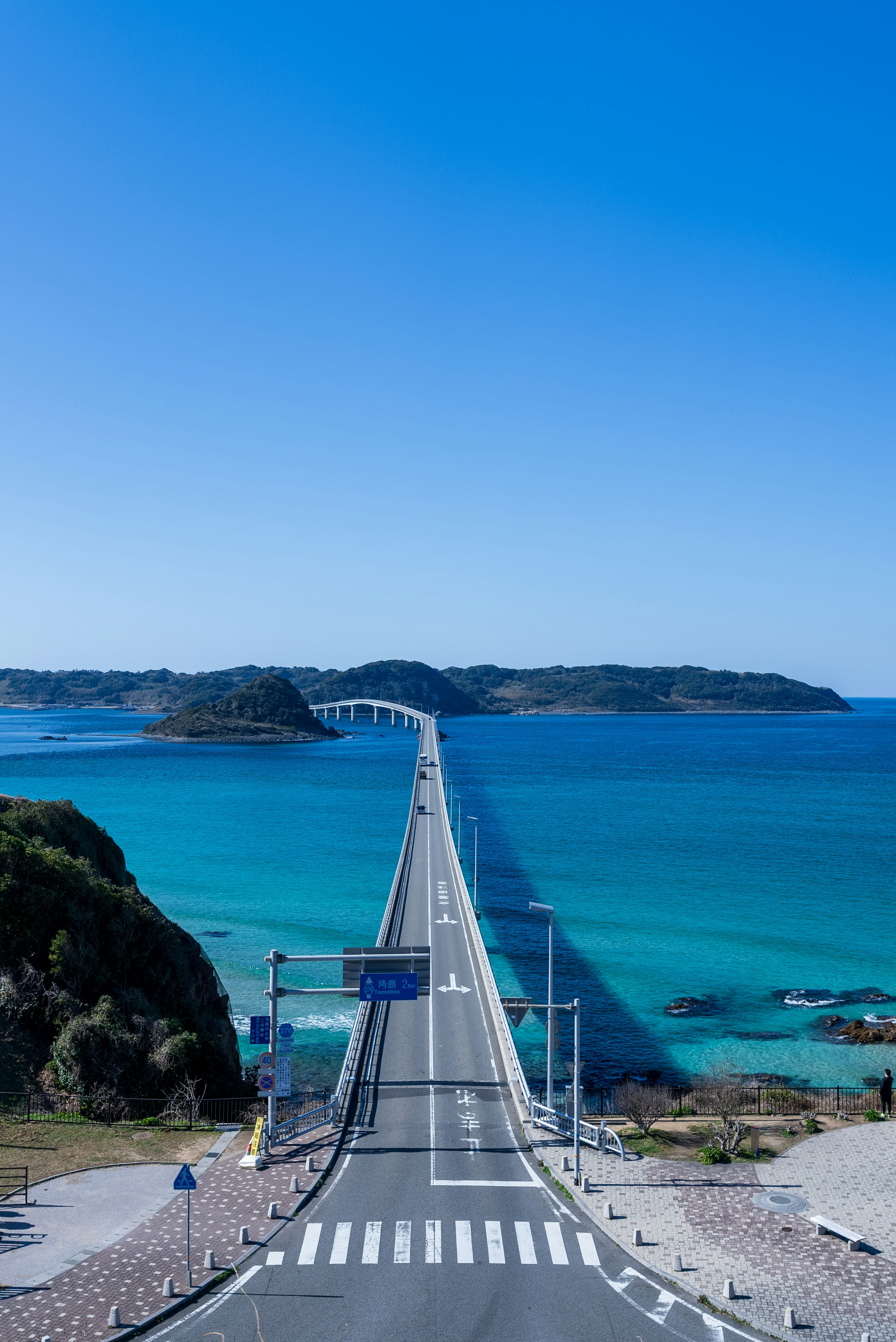 Scenic view of a bridge extending over turquoise waters under a clear blue sky