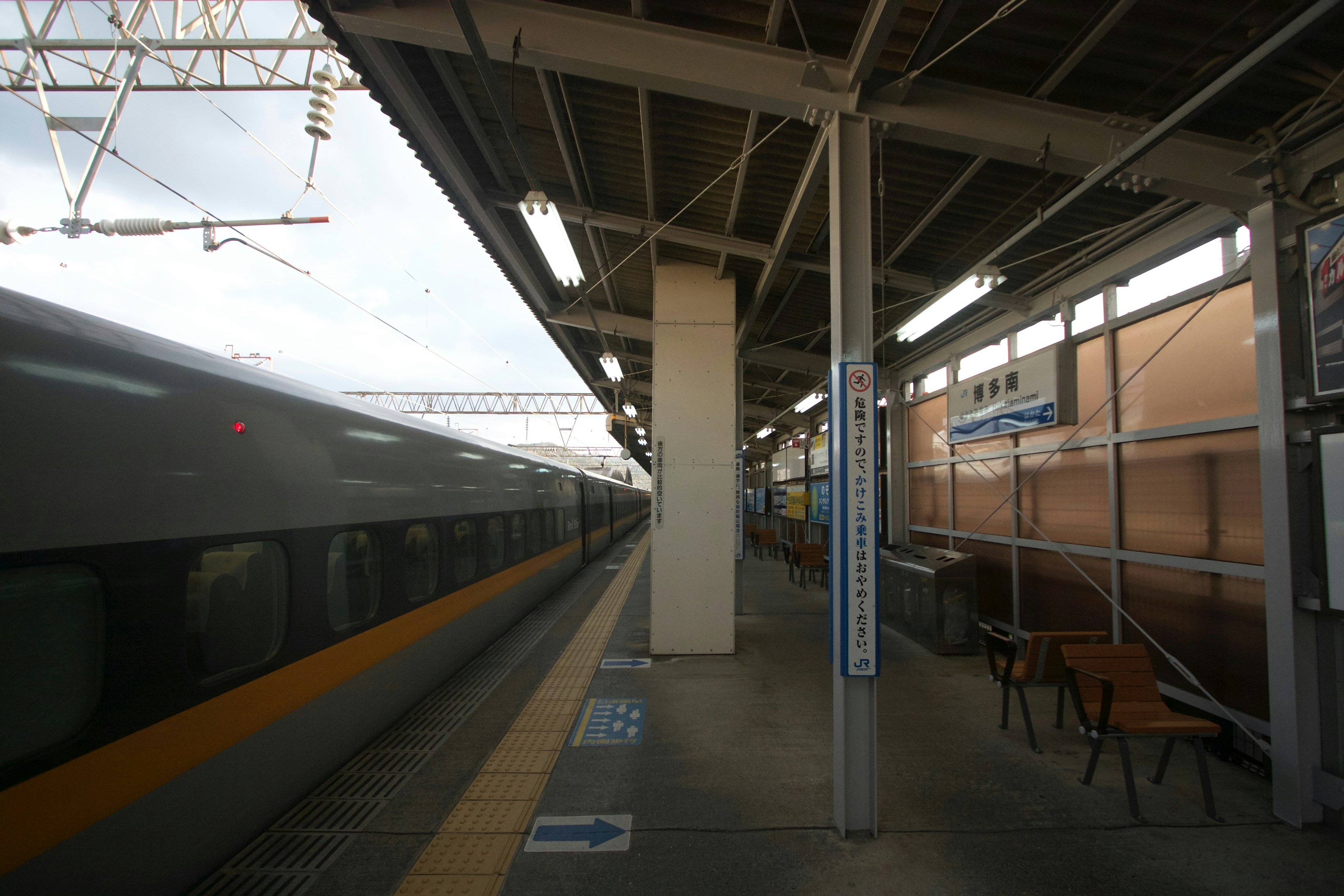 駅のプラットフォームに停車中の列車と椅子が見える風景