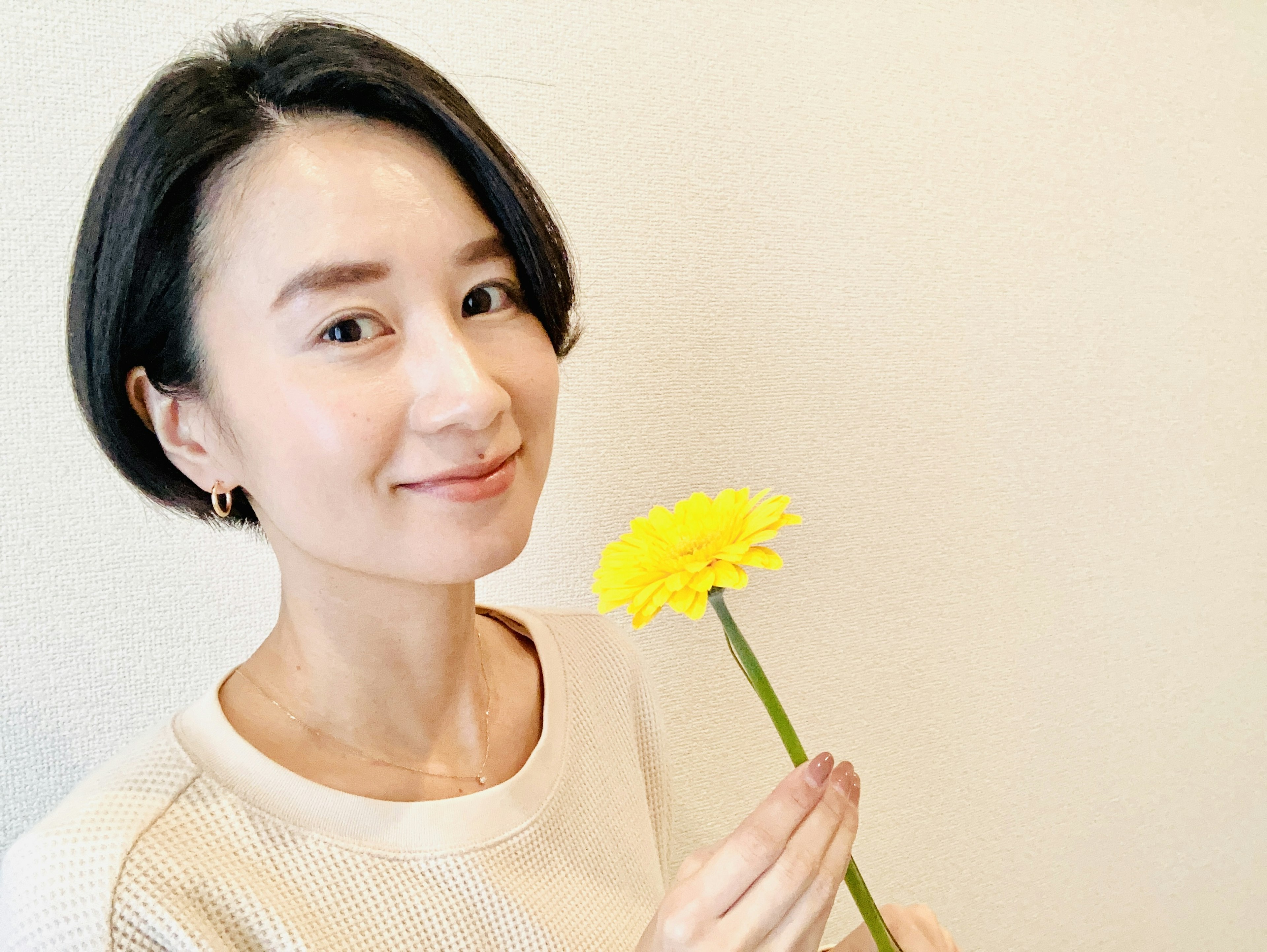 Une femme souriante tenant une fleur jaune