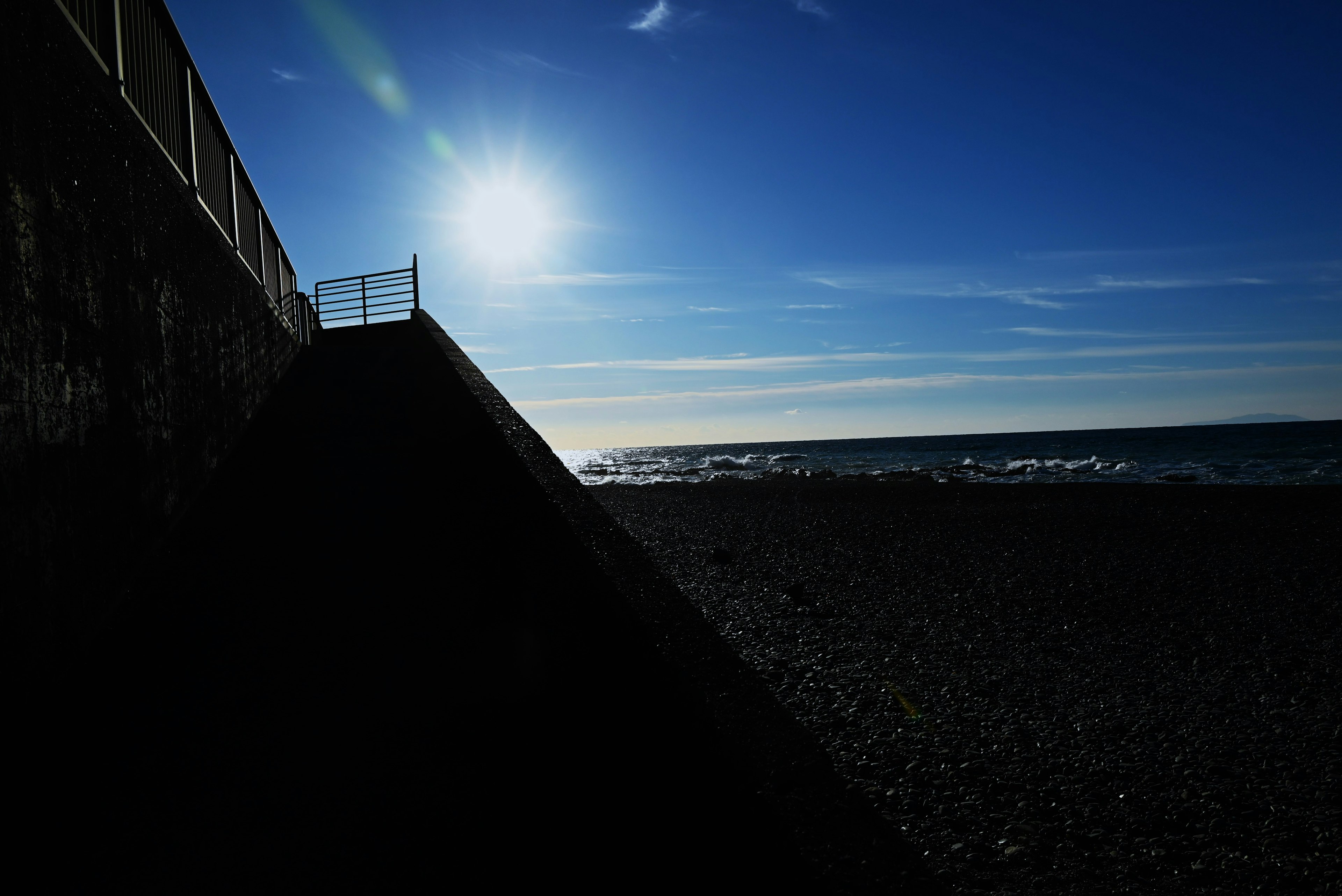 Silhouette of a coastline with sunlight reflecting on the sea