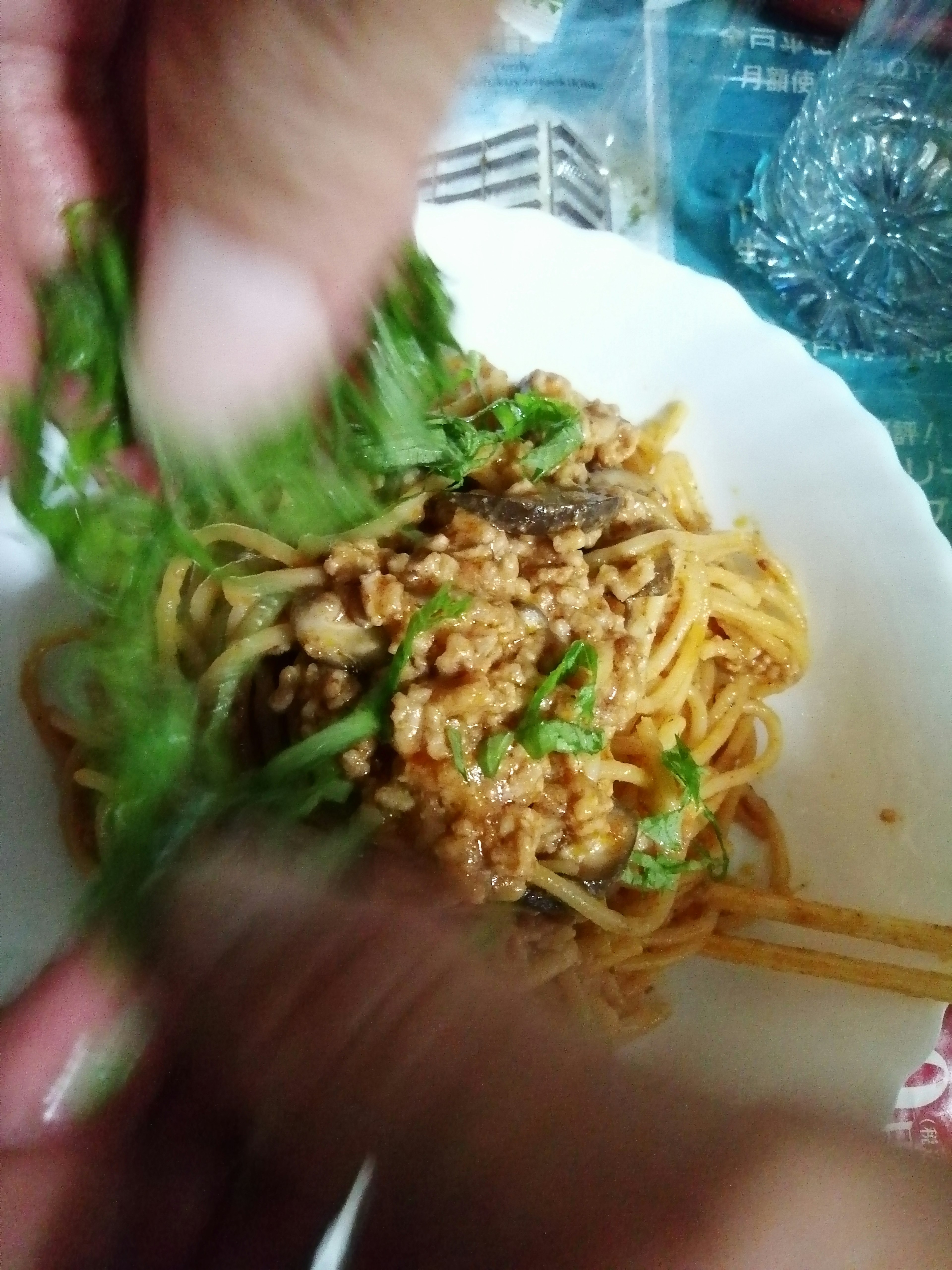 Manos añadiendo hierbas frescas a un plato de pasta