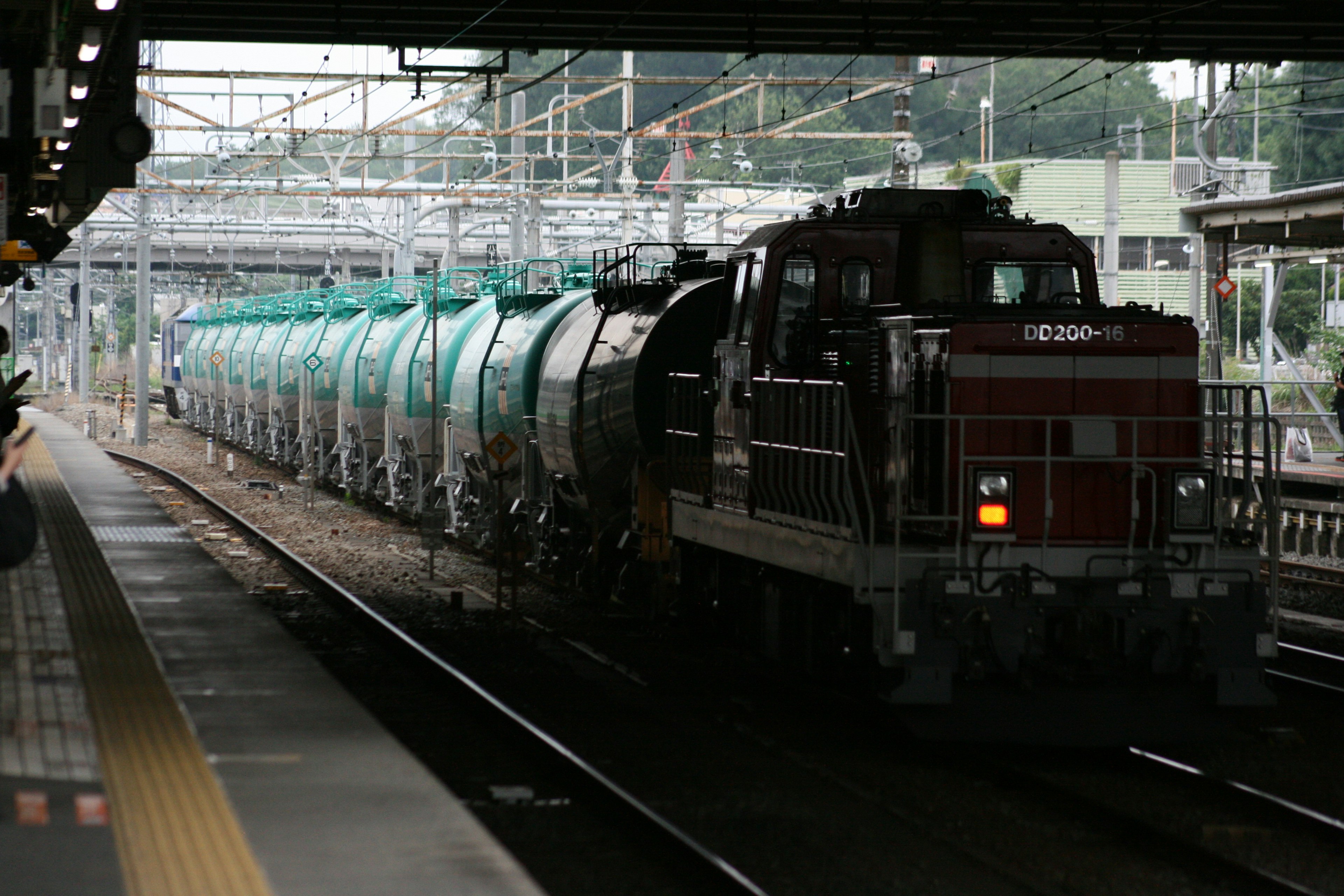 Locomotiva diesel rossa che traina carrozze cisterna verdi in una stazione