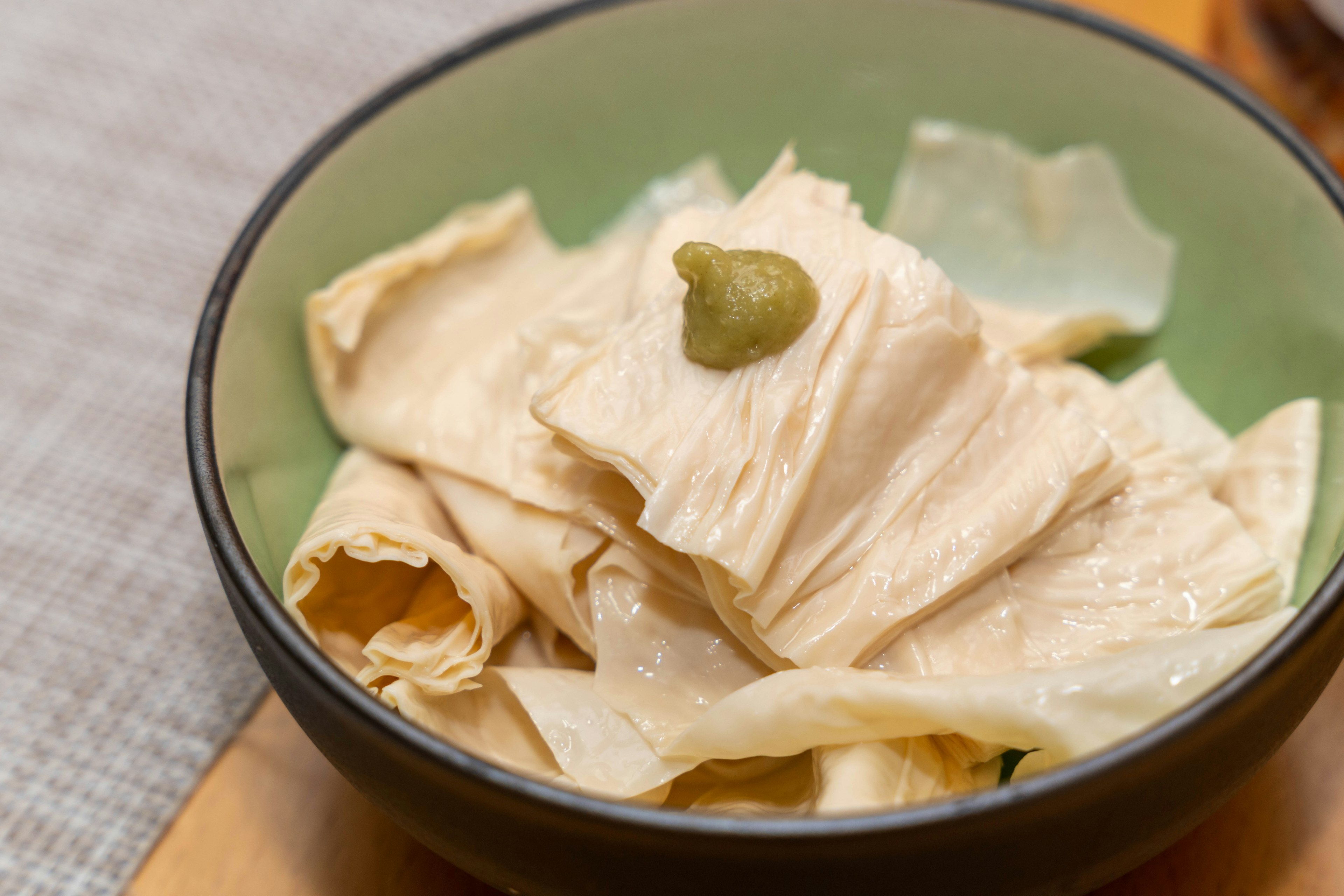 Thinly sliced chicken served in a bowl with a dollop of wasabi on top