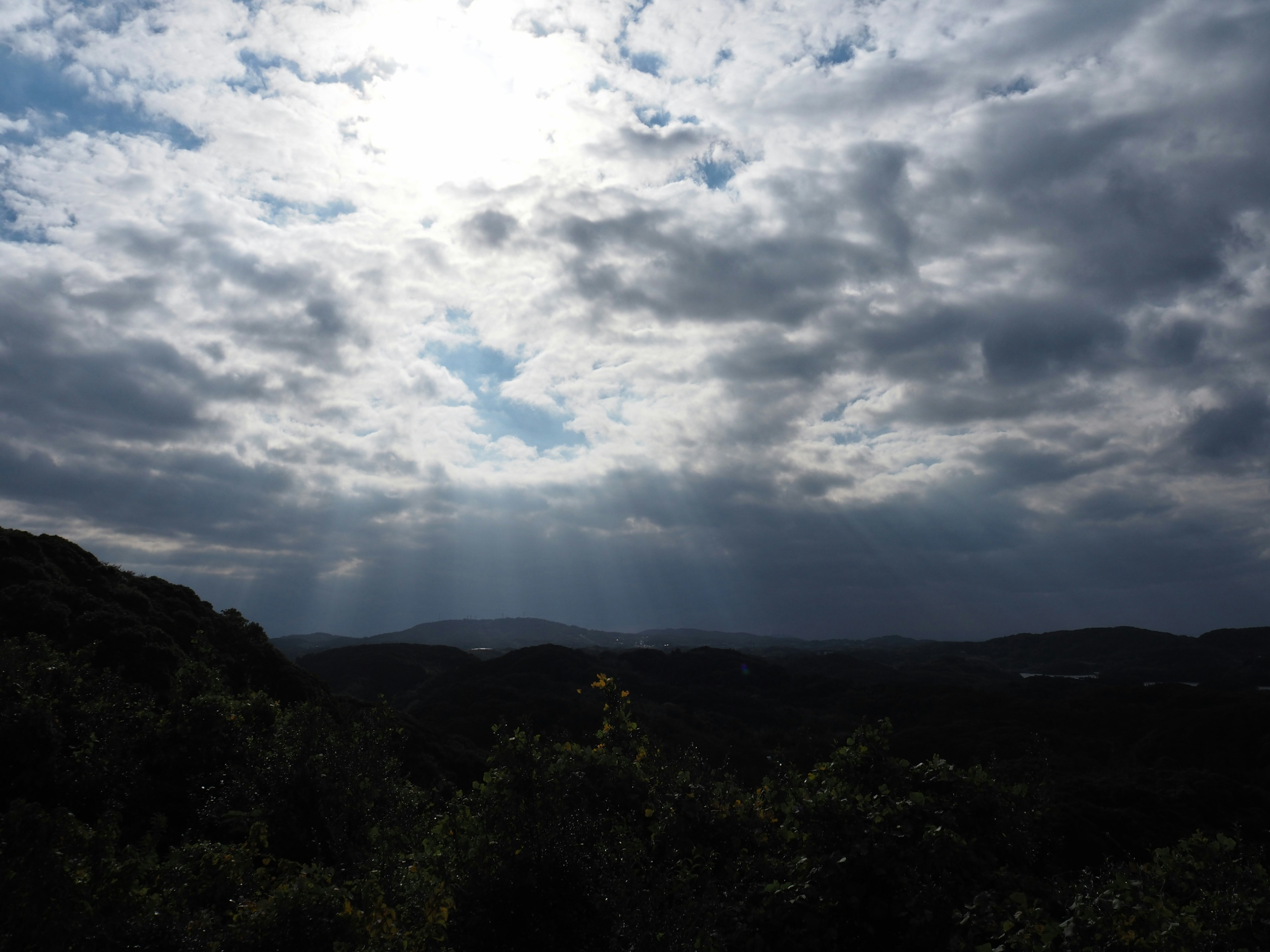 Vista escénica de montañas con luz solar atravesando las nubes