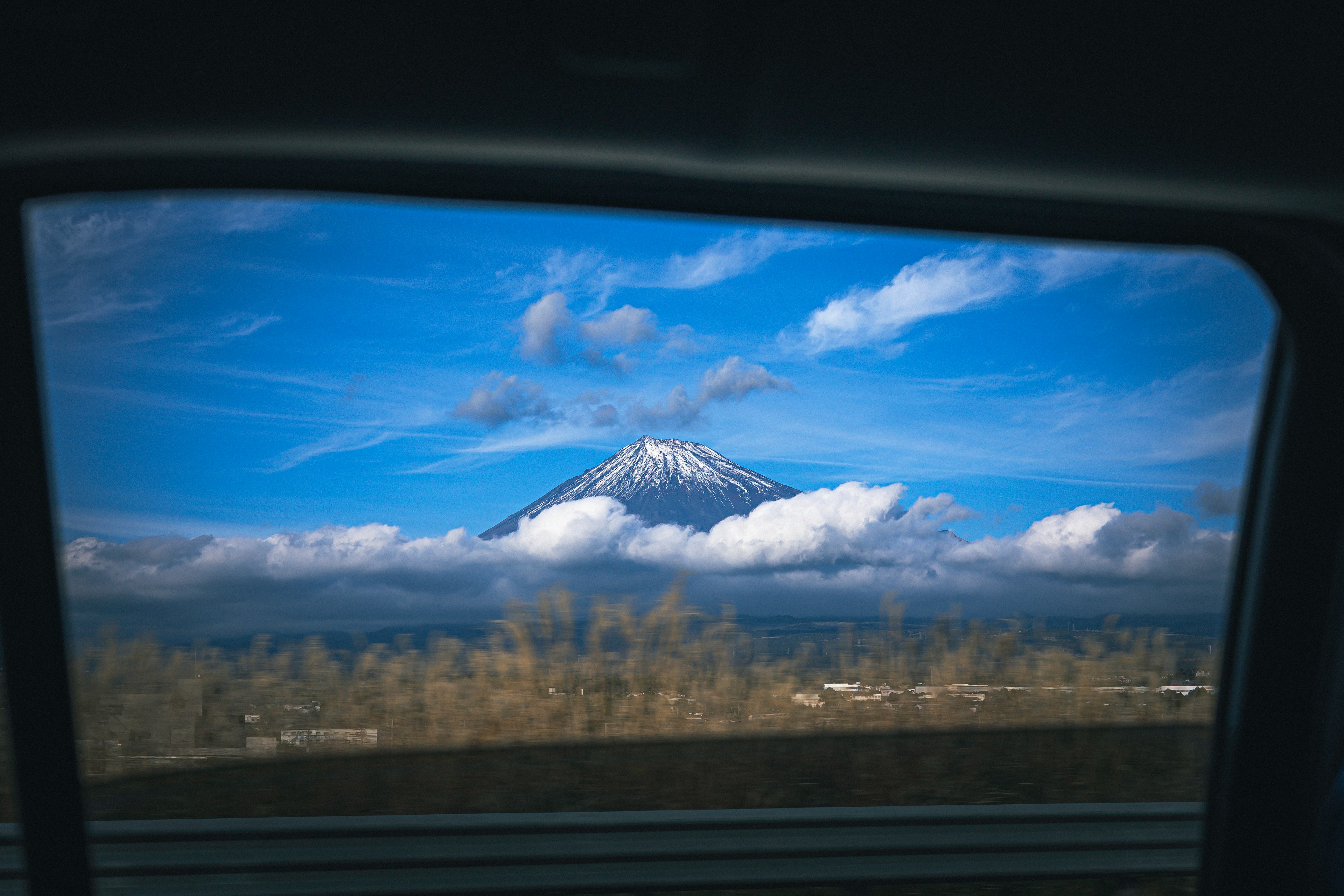 車の窓から見える雪をかぶった山と青空