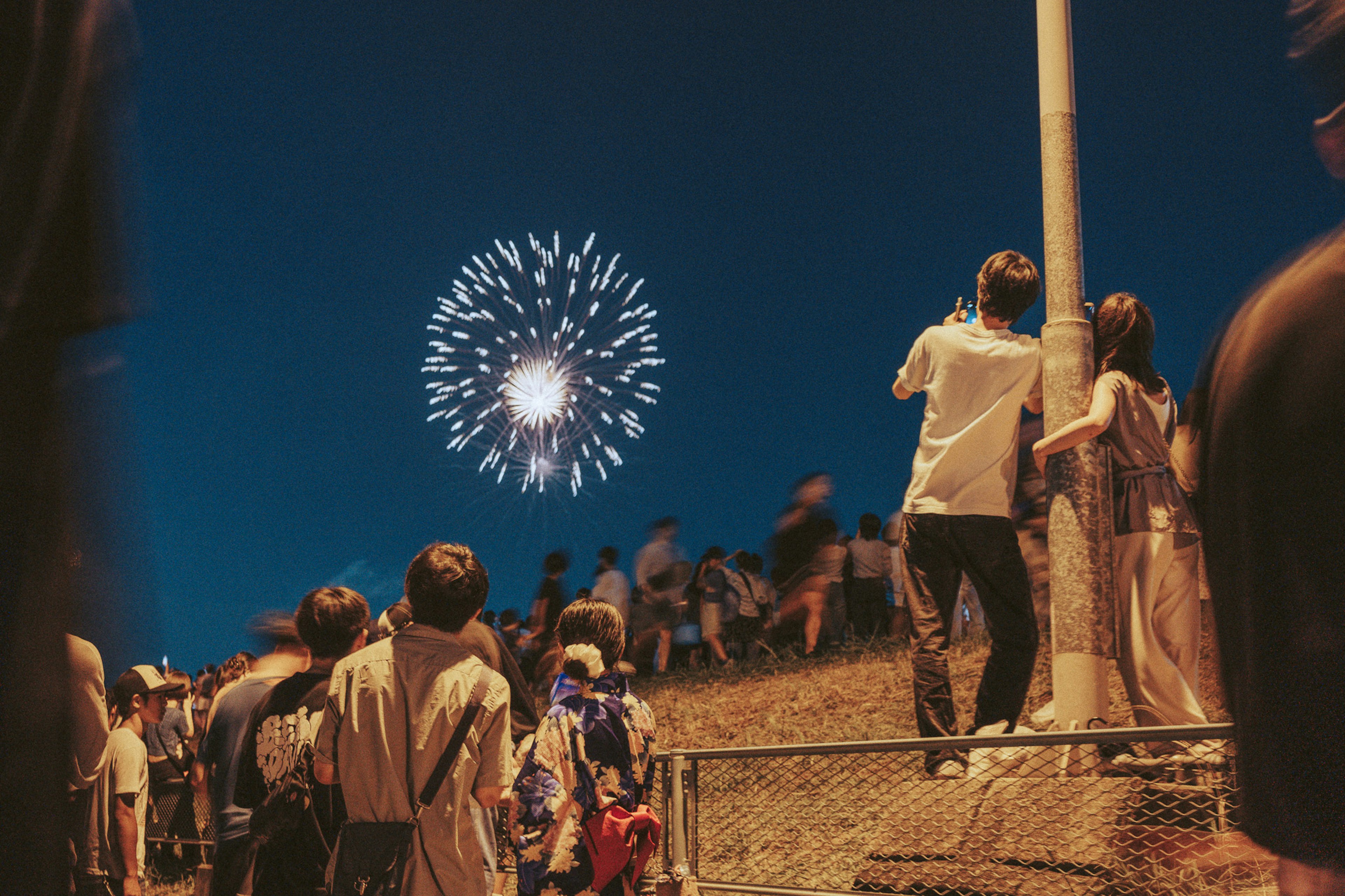 Scene of fireworks lighting up the night sky with spectators enjoying the view