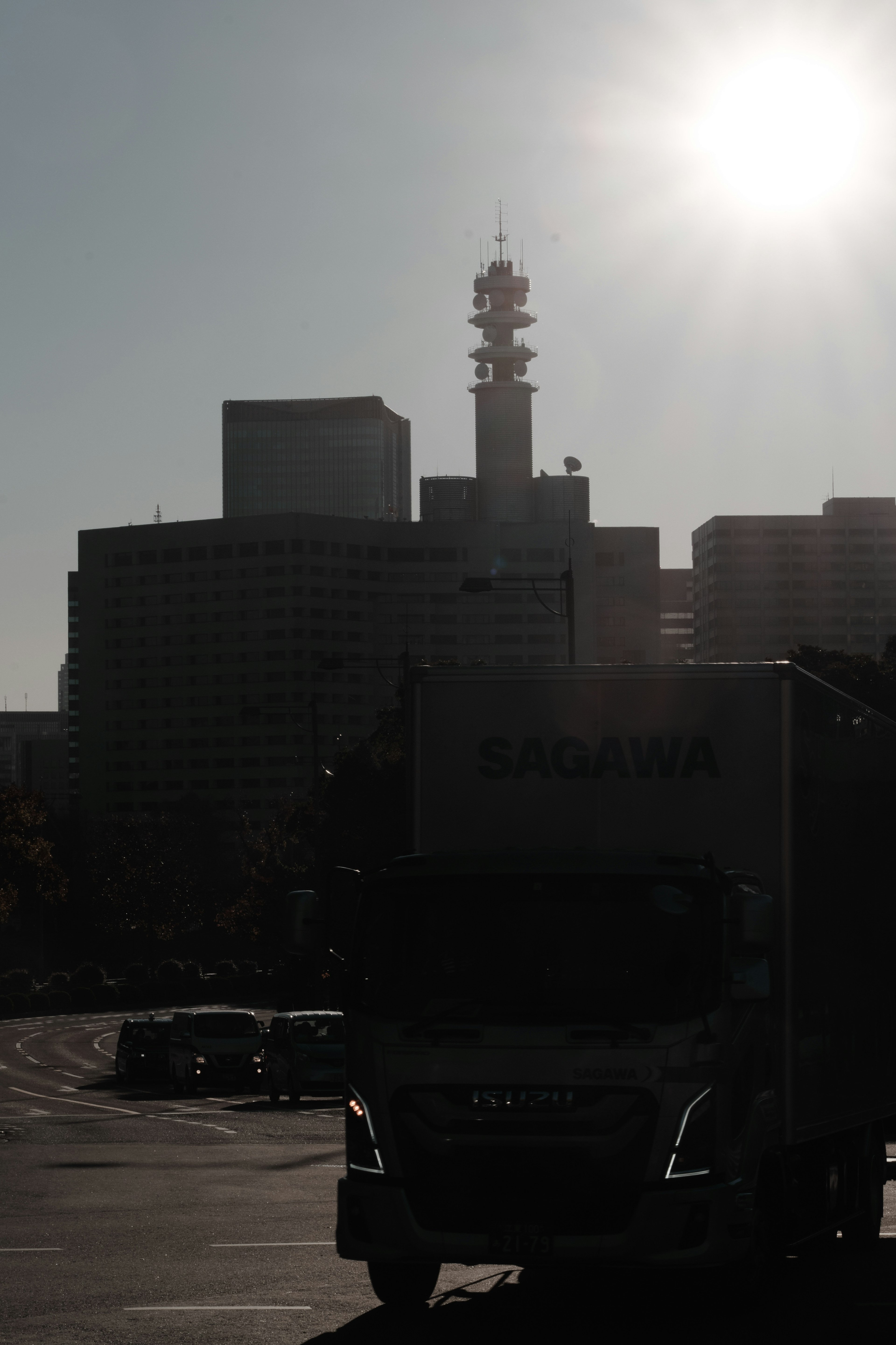 Silhouette of skyscrapers and a truck in the foreground with the sun shining over the cityscape