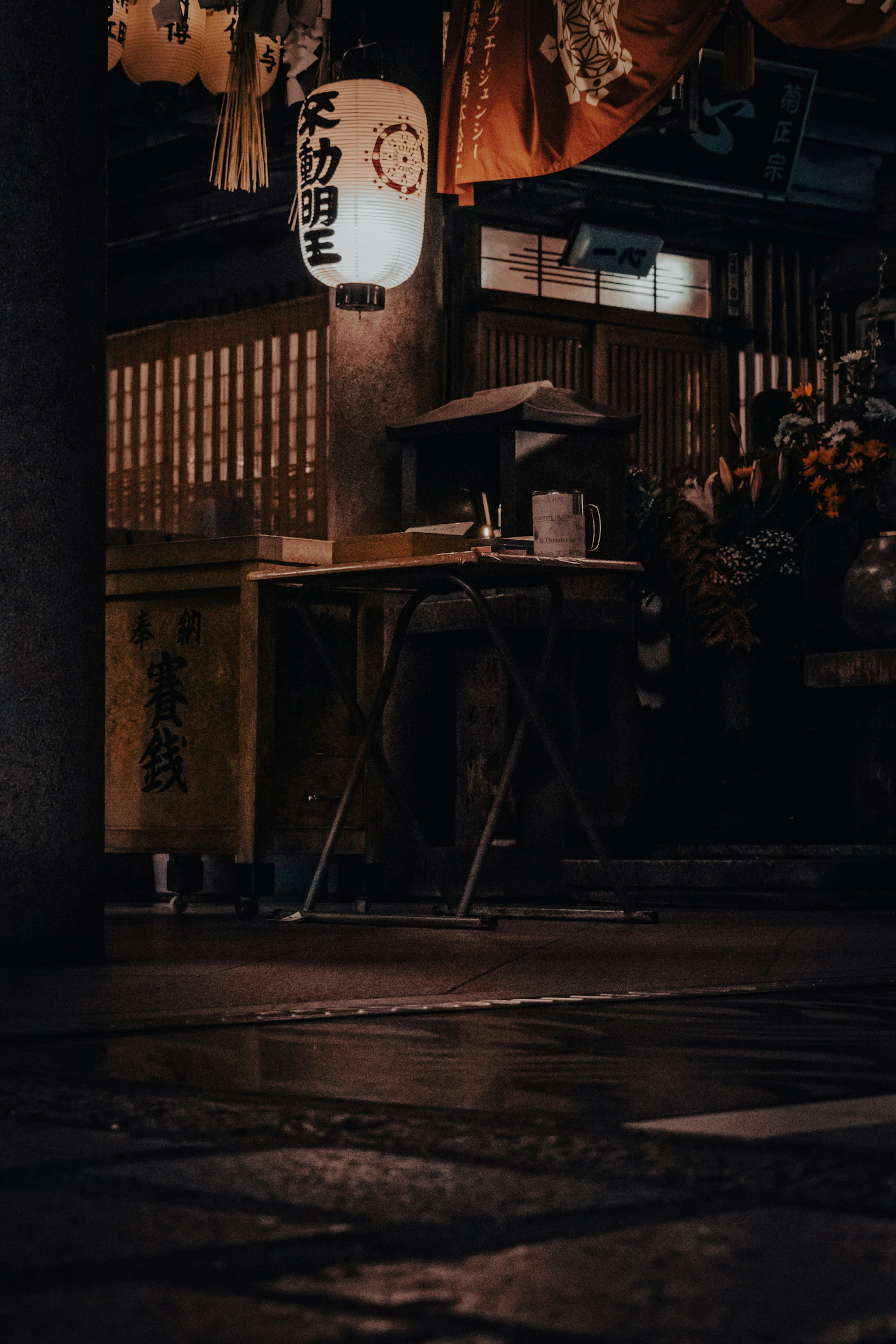 Night scene of a Japanese izakaya with a table and lanterns illuminating the area