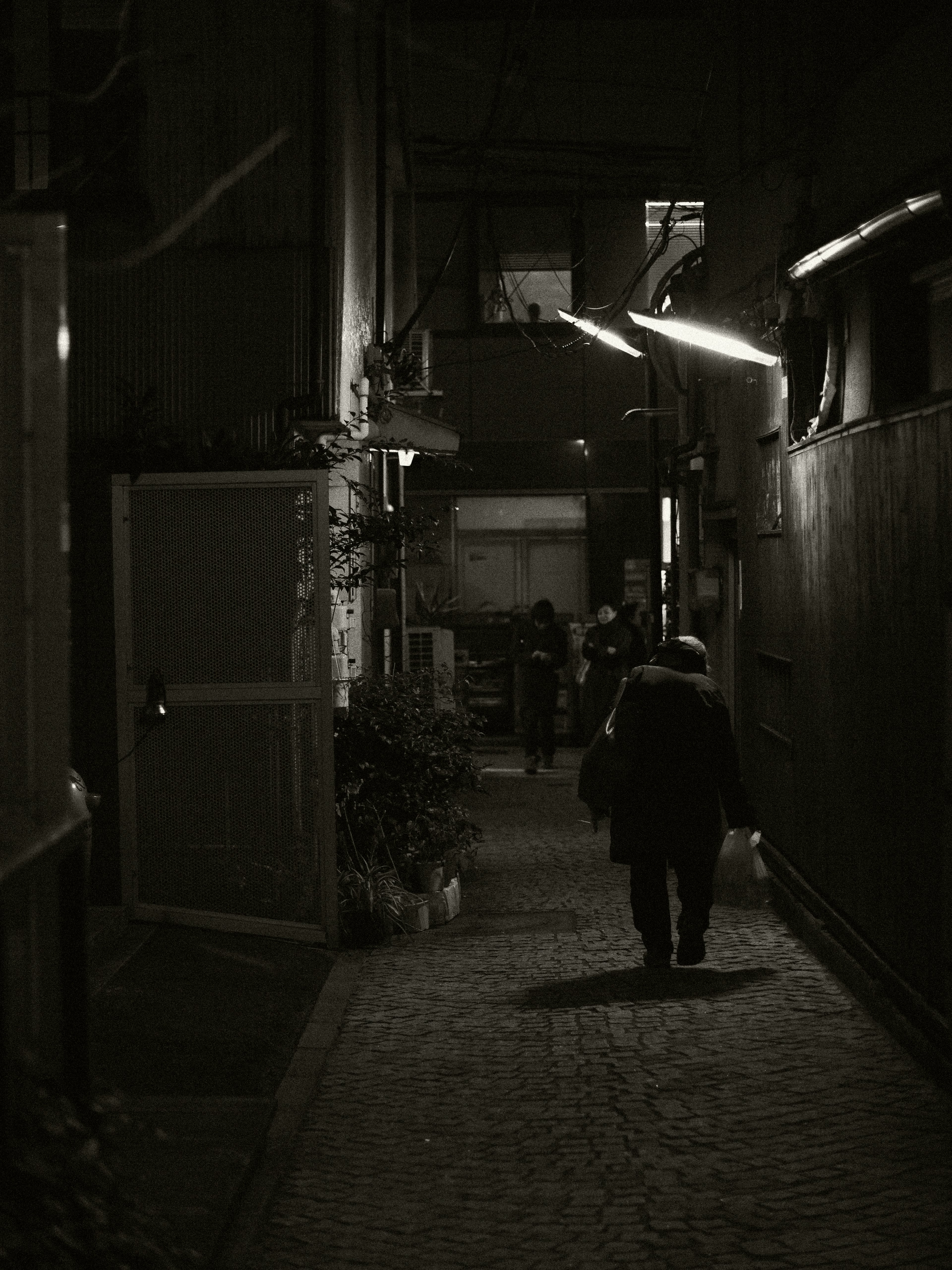 Une personne marchant dans une ruelle sombre avec des bâtiments environnants