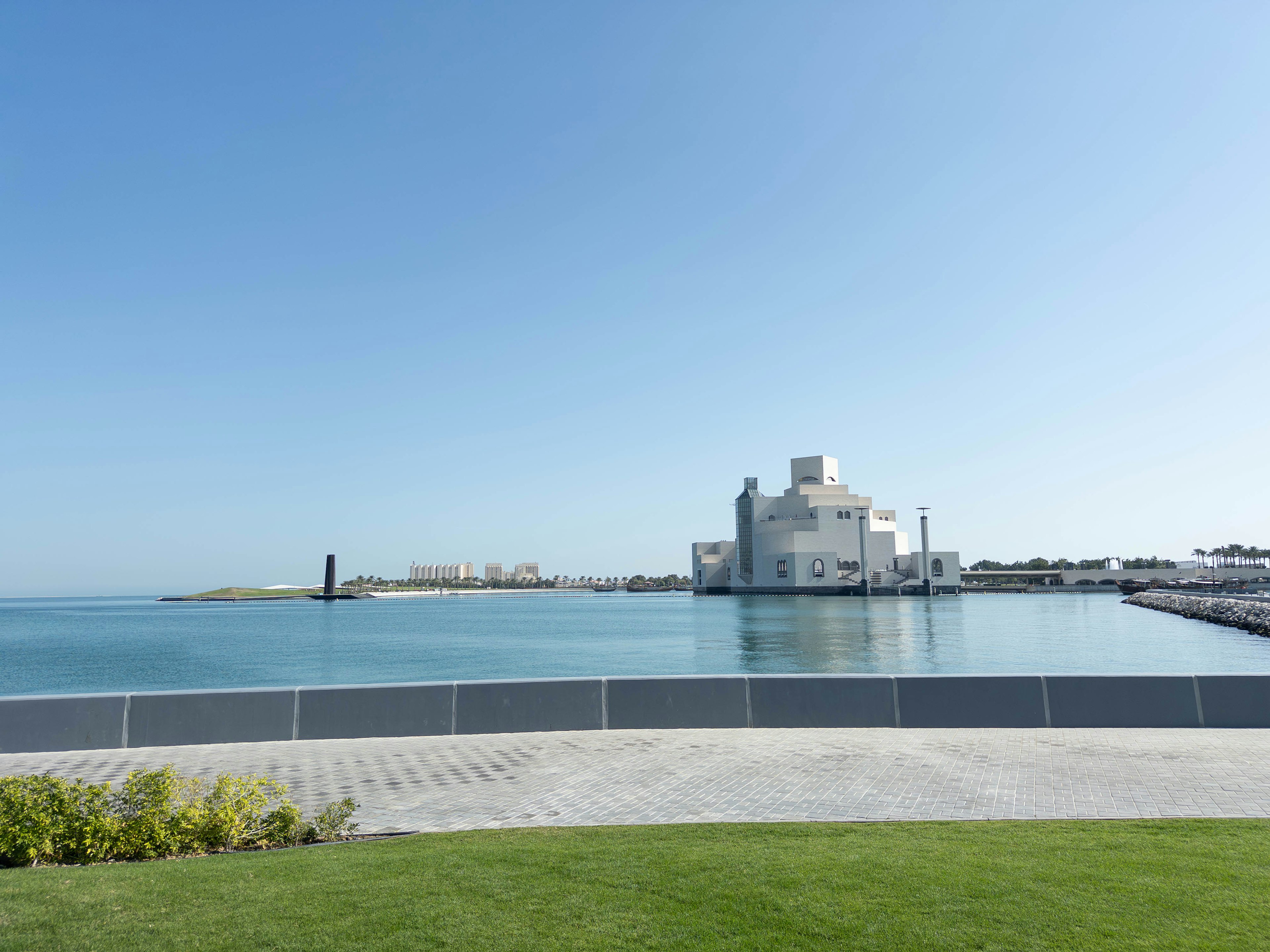 Scenic view of a modern building by the sea under a clear blue sky