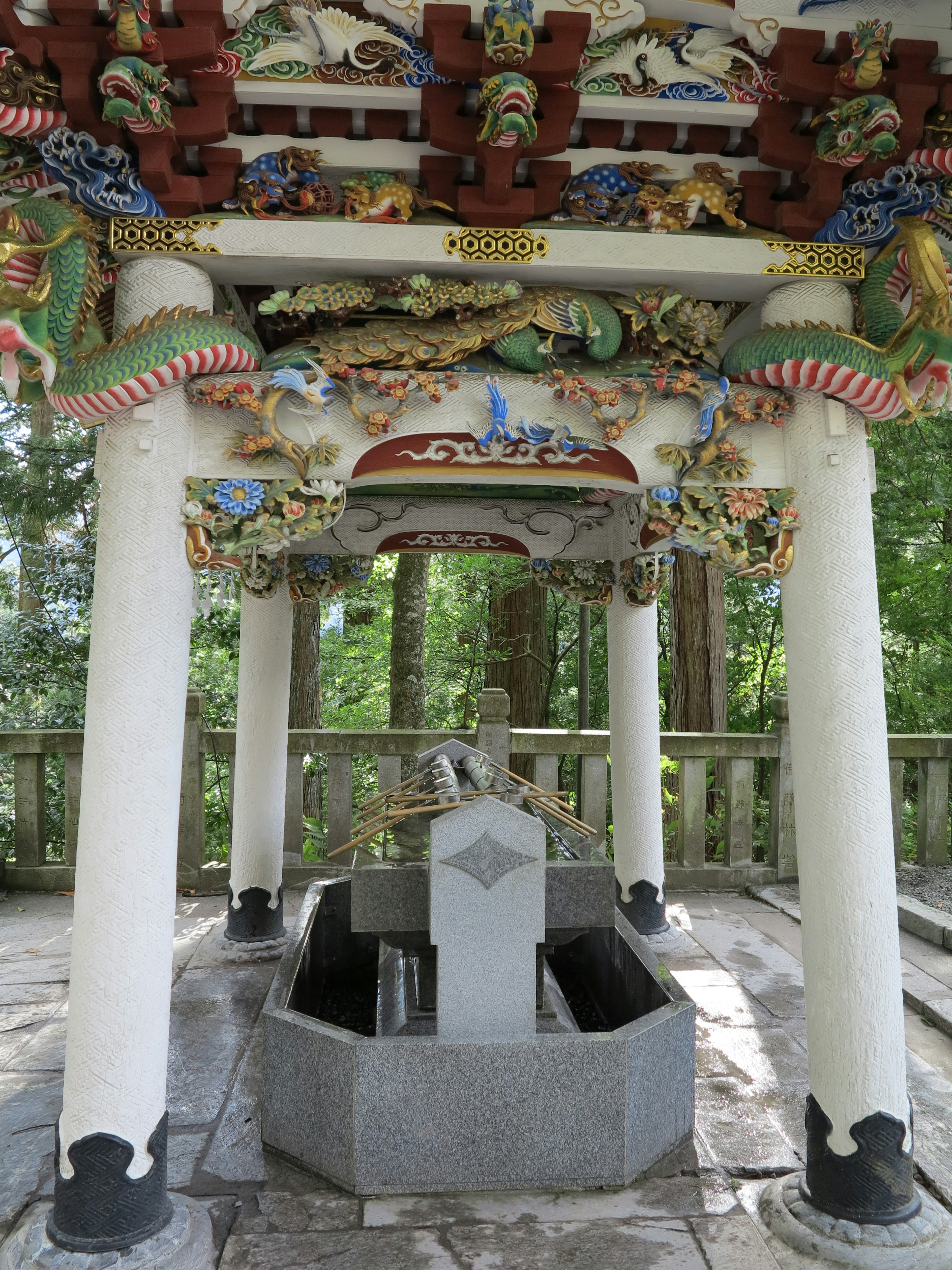 Bacino d'acqua decorativo del santuario circondato da una vegetazione lussureggiante con incisioni intricate