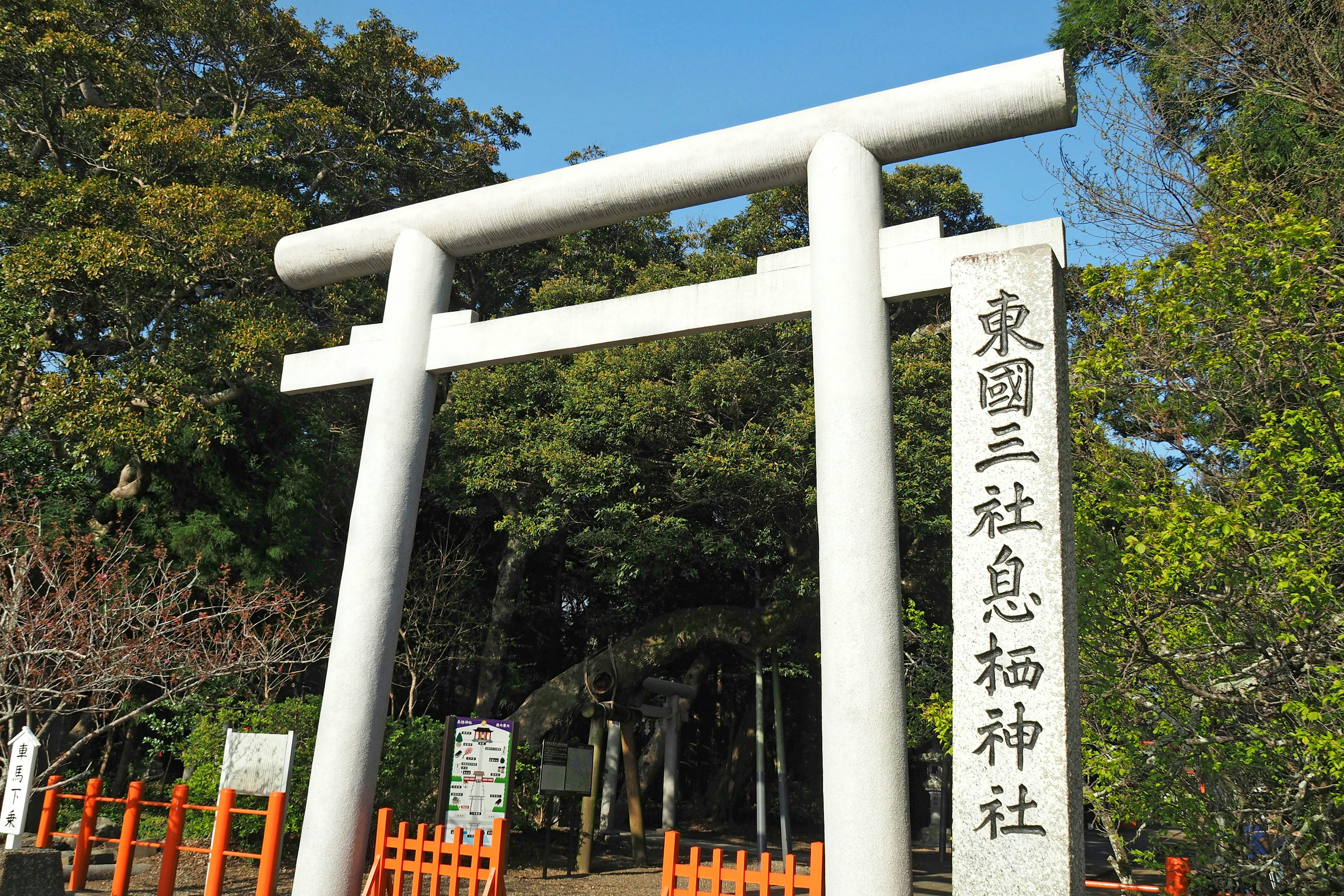 White torii gate with surrounding green trees at Higashi-en San-sha Sume Shrine