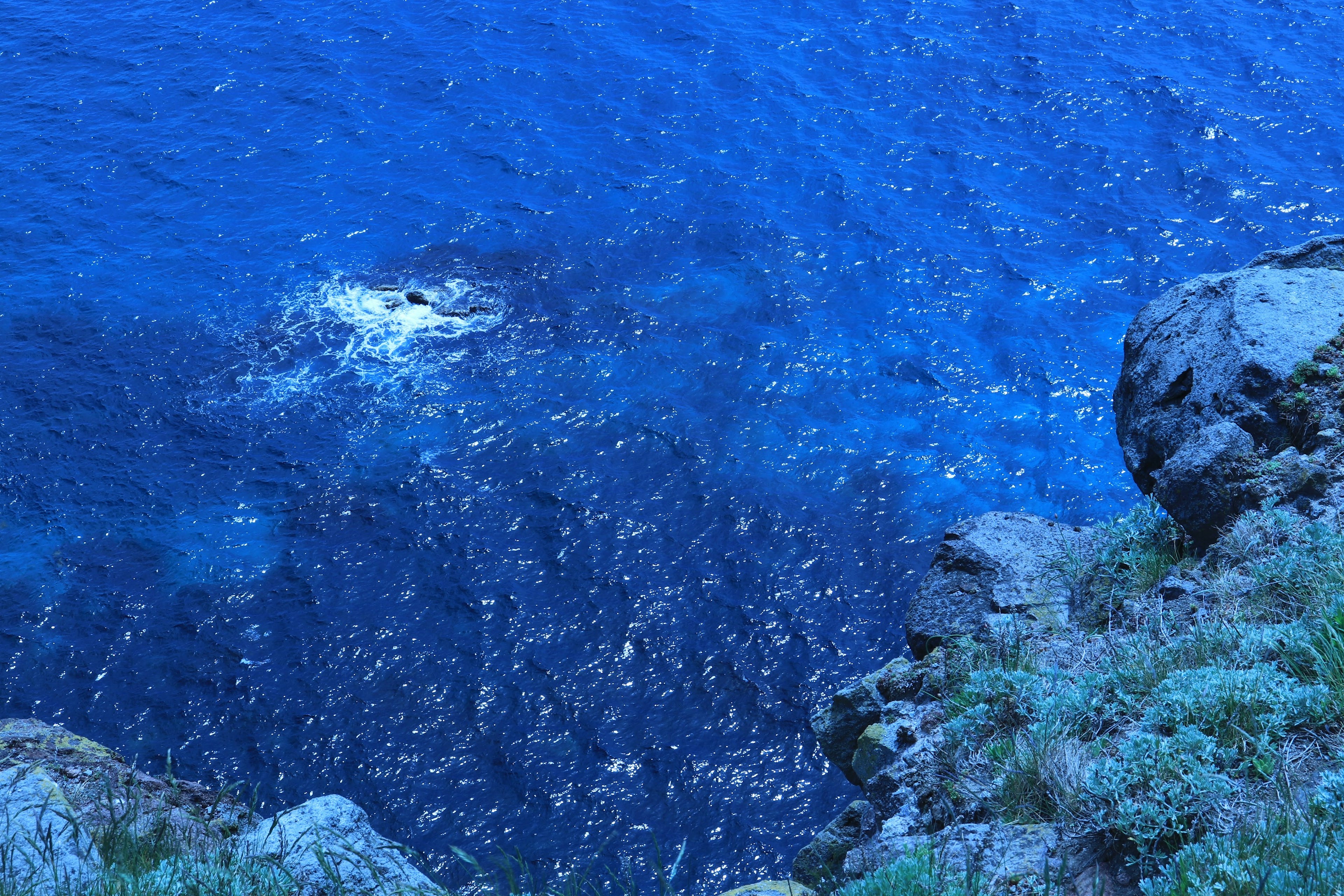 Blick auf den blauen Ozean mit Felsen schimmernde Wasseroberfläche