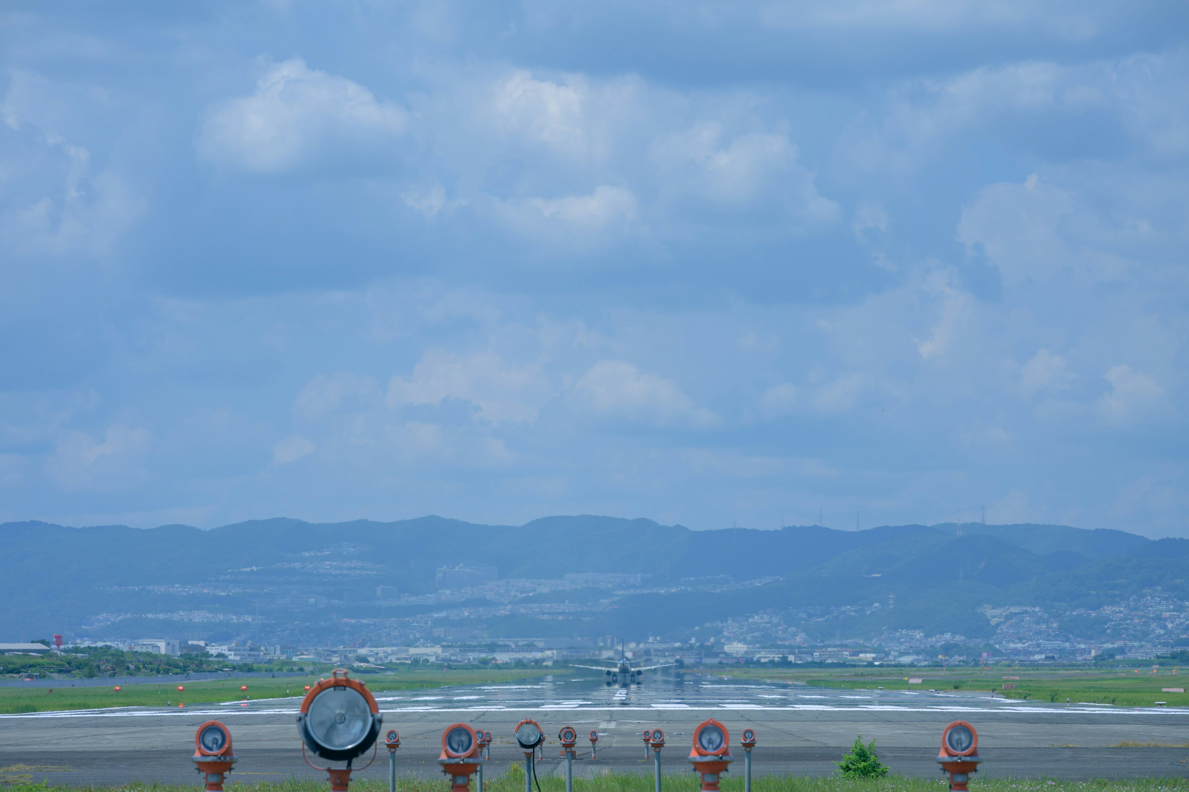 Flugzeug, das von einer Landebahn abhebt, mit umliegenden Lichtern und blauem Himmel