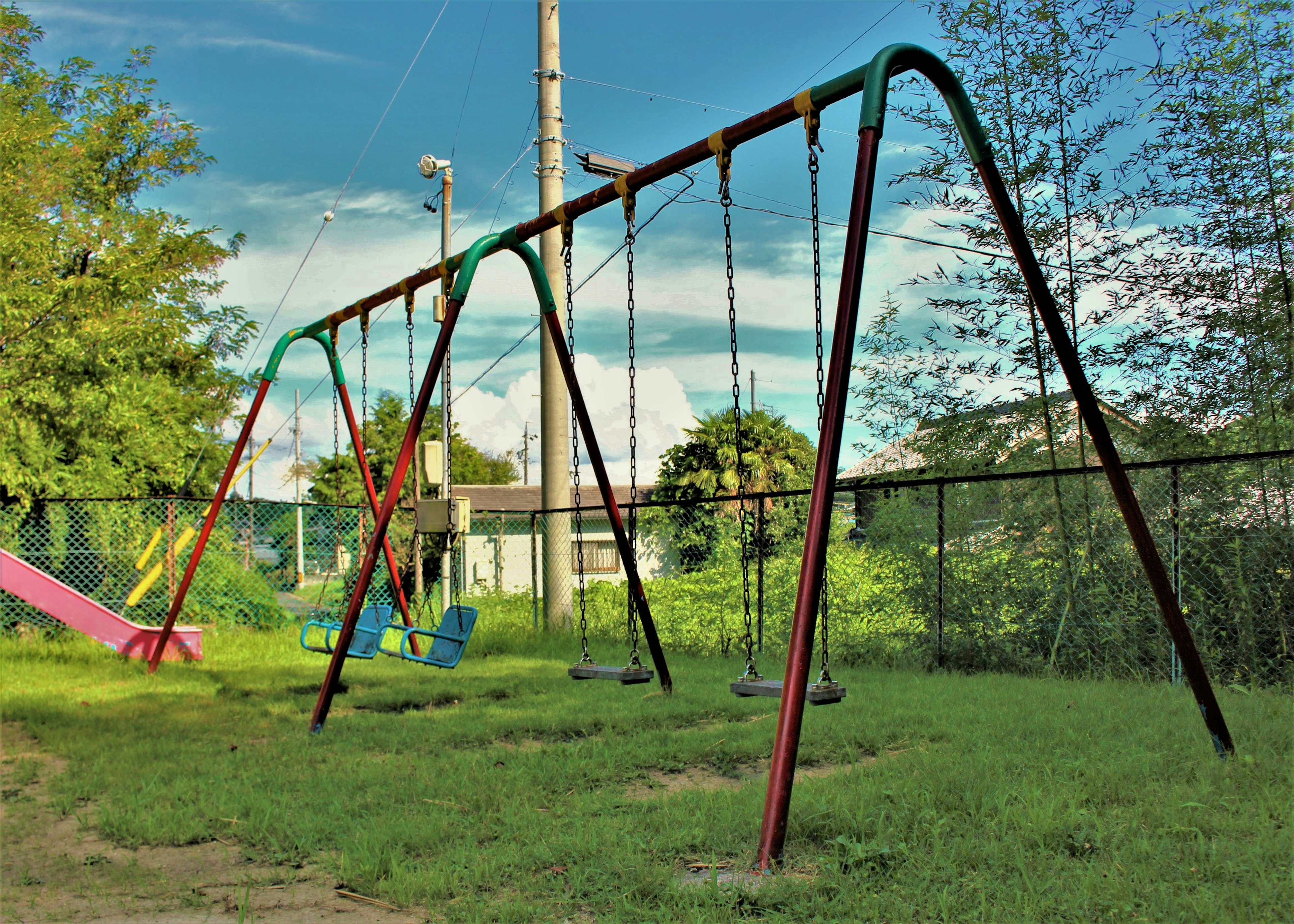 Columpio de parque con césped verde y árboles