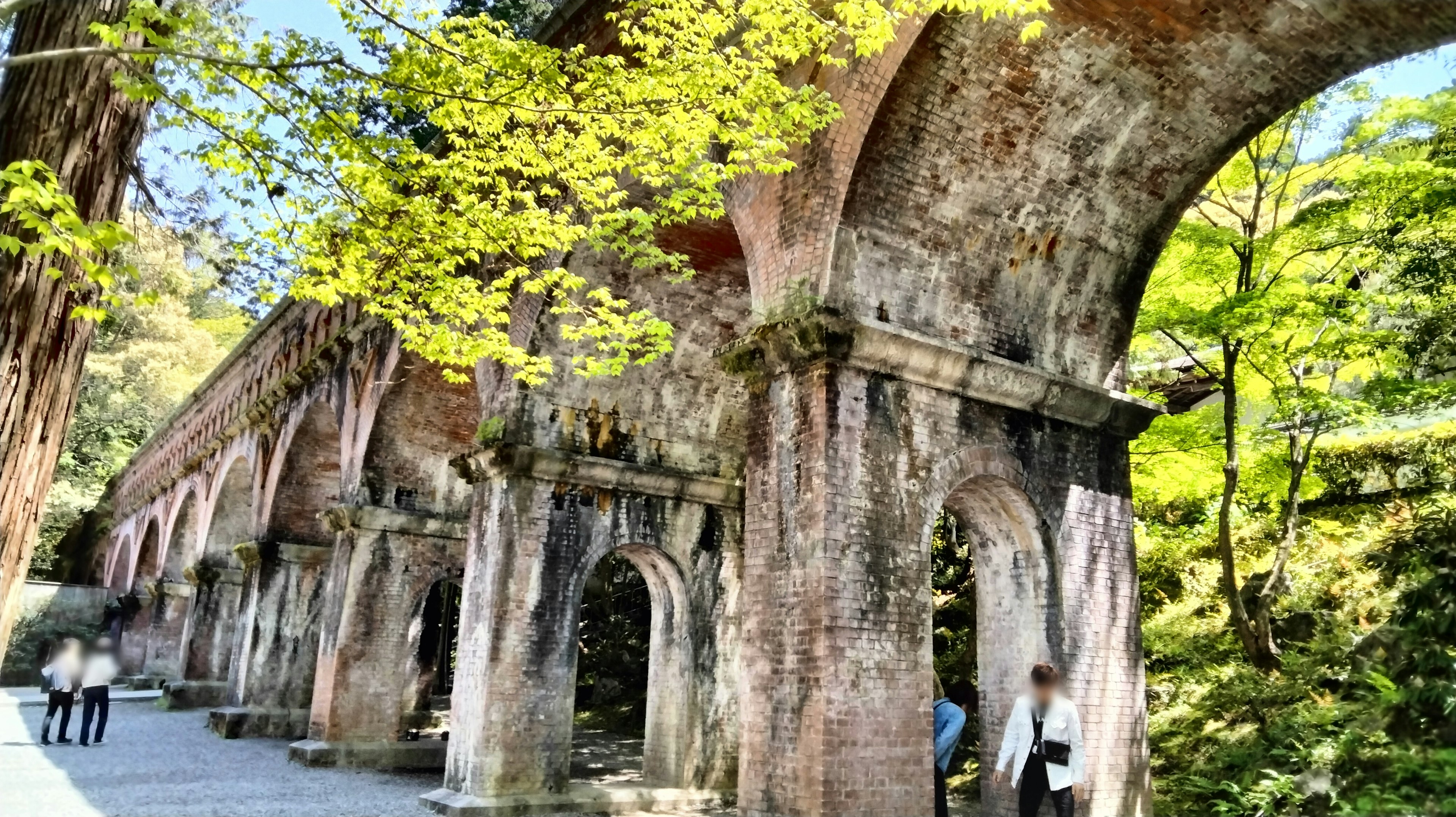 Ancien pont en arc entouré de verdure avec un chemin piéton