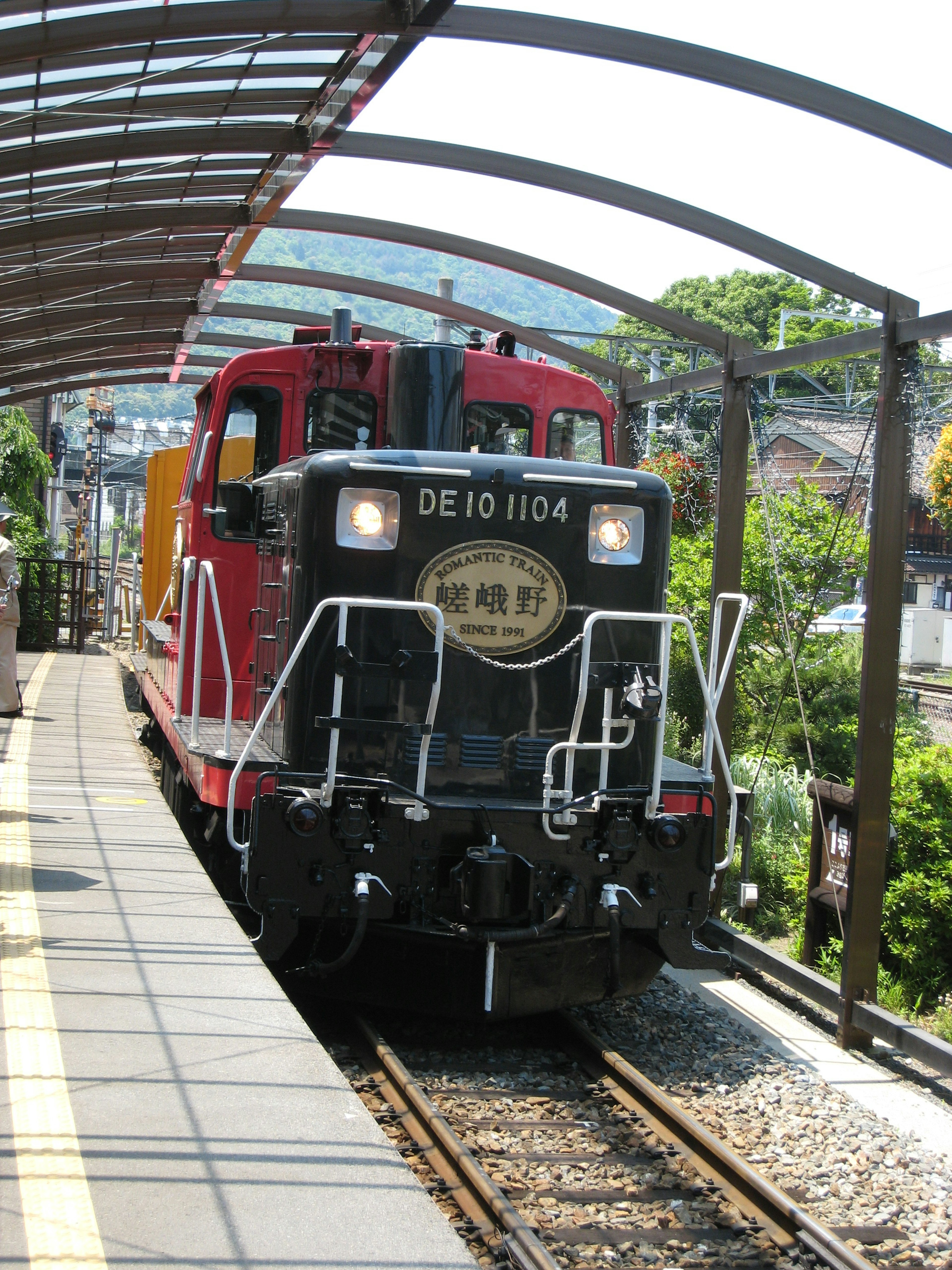 Red diesel locomotive DE1104 at a train station