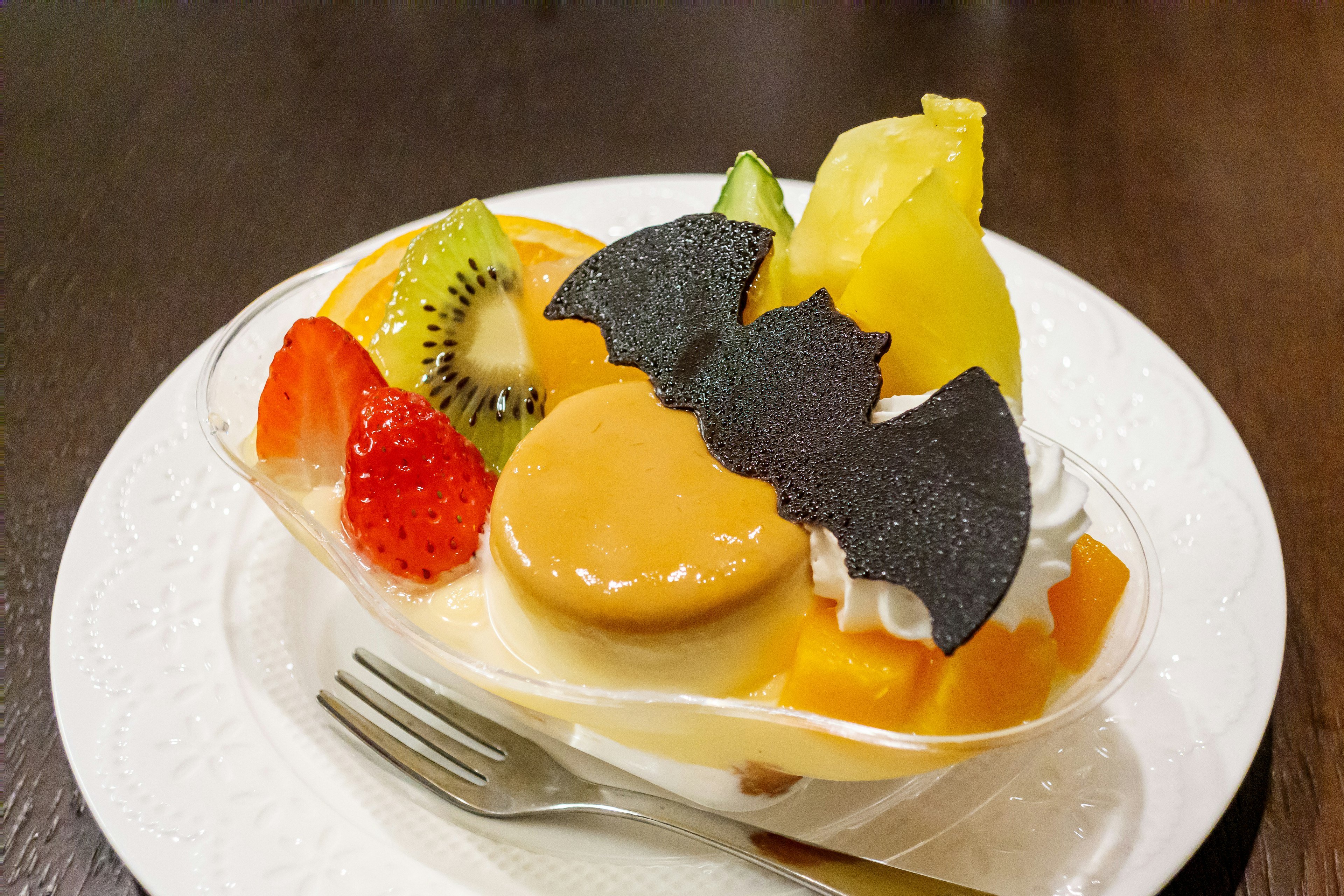 Postre colorido con frutas y una decoración en forma de murciélago